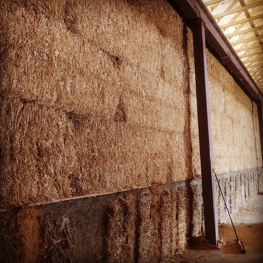 #explaining #howwebuiltthis #megastrawbale wall
The bottom of this wall is below the ground level outside. Which means there is a retaining wall on the outer edge.
The inside of the bottom needs to support the wide heavy straw wall above...without making the retaining wall unnecessarily wide. So there is a platform built with log cutoffs, installed like table legs. The logs are held back off the face of the wall by about 2-inches.
A regular 18-inch #strawbale is wedged between each log. And then the log is covered with a mixture of clay soil and lots of straw fiber. This allows the interior plaster to be applied without the need for any lathing.
Above the wall is just #jumbobales stacked like bricks. They are 3-feet thick and very tight. So no need for strapping or pinning or any other stabilizer.
Why did we do this? It was the fastest, least costly way to achieve exceptional energy efficiency, while using as many local materials as possible.
The building is one of several #naturalbuildings at @blackanklevineyards
#bignaturalbuilding #naturalwarehouse #netzero #naturalbuilding #paradigmshift #buildnaturally #yesyoucan
