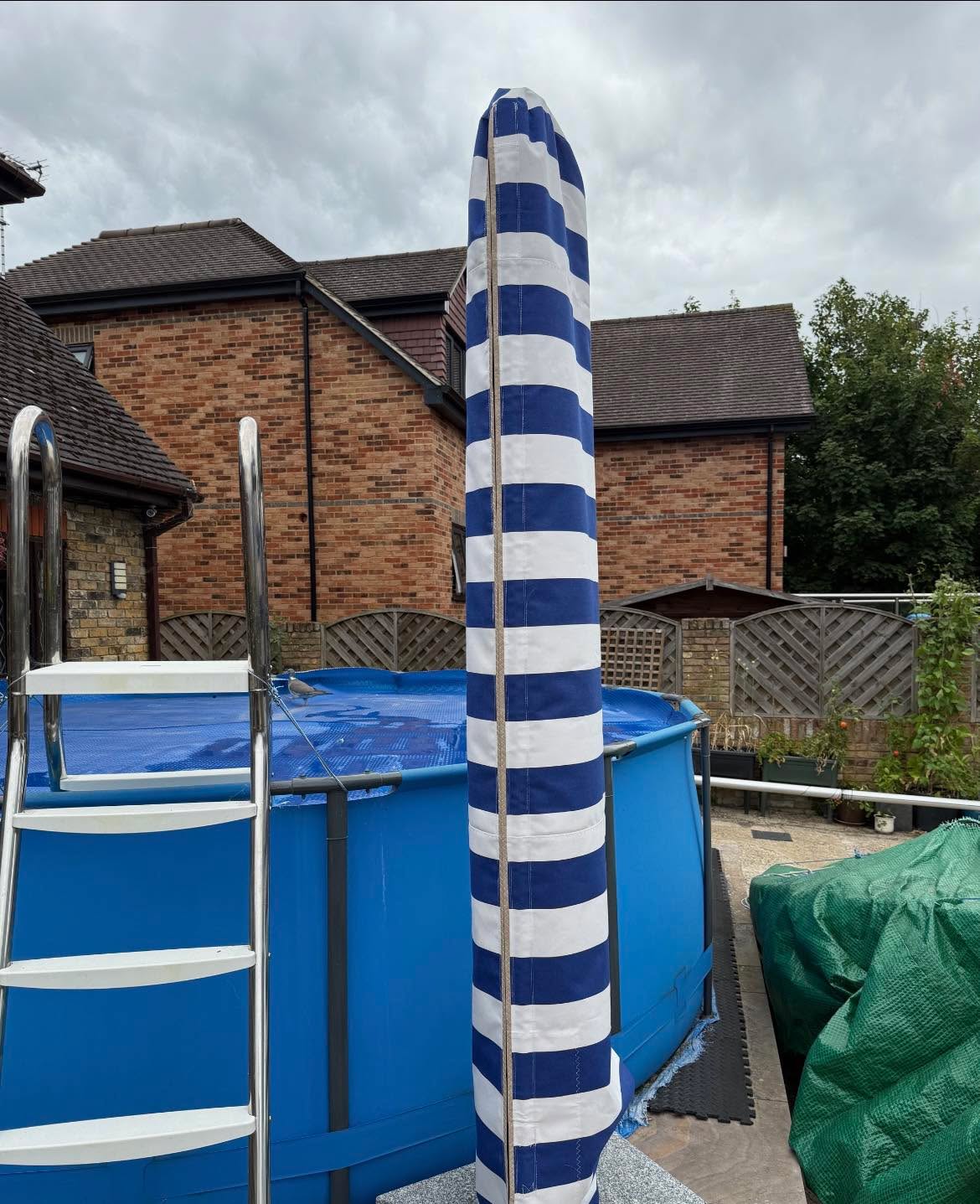 Super striped, white and blue so bright,
Parasol cover that's a pure delight,
Pocket for pole, zip down with ease,
Fitting's a snap, if you please!