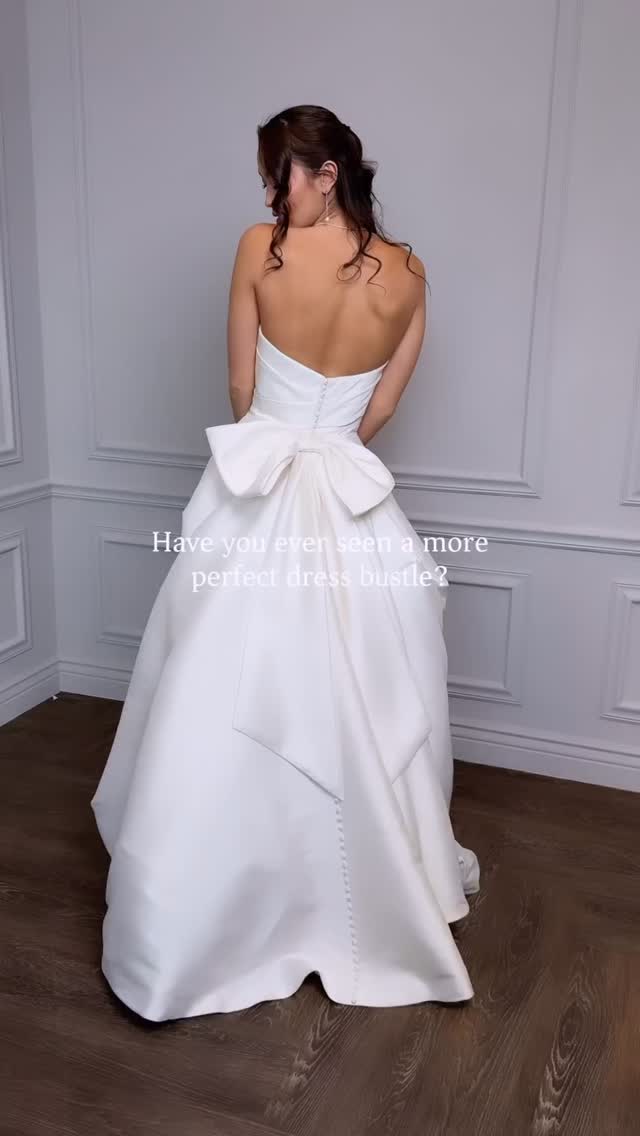 🤍 A clean and crisp beauty, this A-line wedding dress is a fashionable take on the minimalistic trend. This luxurious Mikado A-line features a stylized strapless neckline that is accented with asymmetric pleating. A matching bow on the train adds a unique design detail that loops onto the natural waist to instantly create a perfect bustle. The style is finished with pockets and Mikado covered buttons to the end of the chapel length train.✨