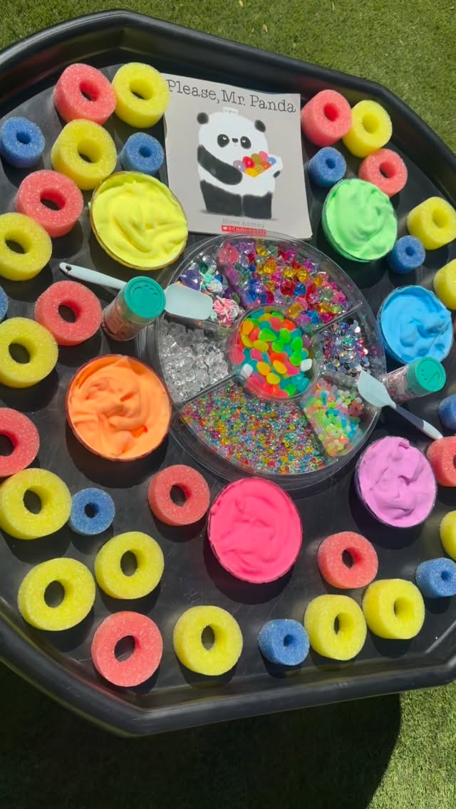 Please, Mr. Panda: A Sensory Doughnut Invitation// Inspired by Please, Mr. Panda by @mrsteveantony, this invitation took the story beyond the pages & into play, inviting children to create, decorate & imagine their very own doughnuts through hands-on exploration.
In the story, Mr. Panda offers a tray of colorful doughnuts to his animal friends, but there is one very important word they keep forgetting: please! Beyond its humor & simple illustrations, the story opens up a natural conversation about manners, kindness & communication.
And, of course, all of those colorful doughnuts were just asking to become an invitation to play!
I cut pool noodles into slices to create pretend doughnuts and arranged them on our @discountschoolsupply #TuffTray alongside the book. Shaving cream mixed with @colorationsart Fluorescent BioColor® Paint became vibrant, fluffy “frosting” to scoop, spread, swirl & layer.
Our Tinker Tray was filled with resin sprinkles, acrylic rocks, glow-in-the-dark pebbles & gems galore, giving children the freedom to decorate, create patterns & dream up their own unique doughnuts.
Children could create doughnuts for Mr. Panda, offer them to one another, imagine which toppings each character might like & retell parts of the story through play.
And within all that decorating was so much learning! Scooping, spreading, pinching, pressing & sprinkling strengthened #finemotorskills & hand-eye coordination, while the open-ended materials encouraged sensory exploration, counting, sorting, patterning & early mathematical thinking.
This is why I love using children’s books as the beginning of an invitation rather than the end. A story can introduce a character, idea or possibility, while open-ended materials give children the freedom to imagine what might happen next.
The pool noodles became doughnuts. The shaving cream became frosting. The loose parts became toppings. And the story became something children could touch, transform & make entirely their own.
That is the beauty of extending children’s literature through play, giving children the materials, space & freedom to carry a story beyond the pages & into play. #tinkerwonderplay #bookishplay