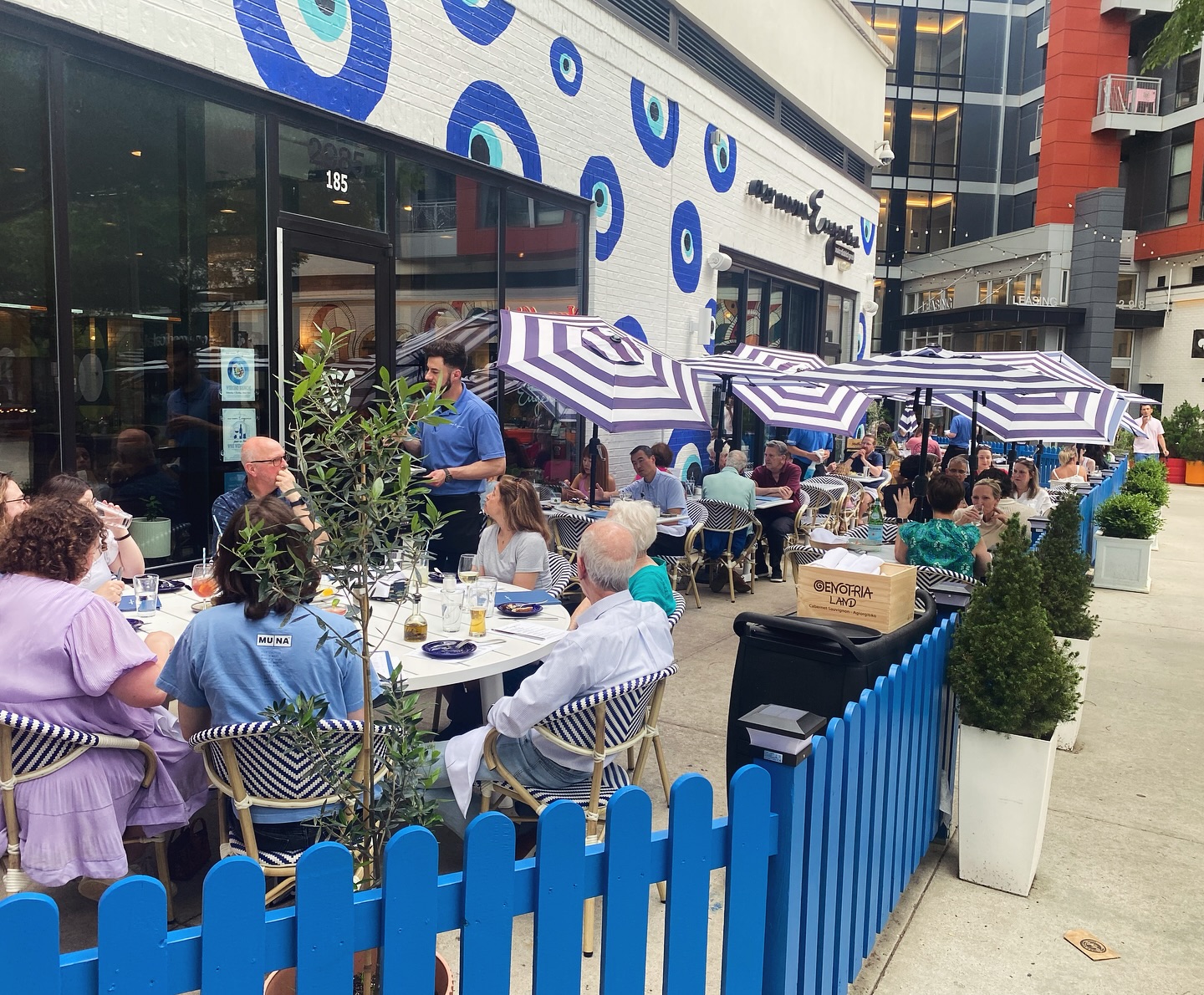 Saturday evening and the sidewalk patio is full. Lively conversations take place as guests enjoy delicious food and beautiful weather. All under the blue-and-white canopy of our capri stripe umbrellas, tilted artfully to evoke a Cristo & Jeanne-Claude installation, right here in @mosaicdistrict . ⛱️💙🧿 #diningalfresco #summervibes☀️