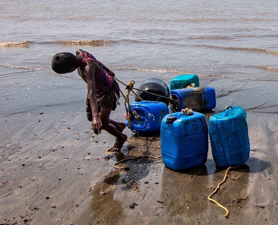 The Weight of Survival, by Santanu Roy (@santanuroy_clicks)
This photo was taken on Mousuni Island, a small patch of land on the southern edge of West Bengal.
Life here moves with the sea, the tides decide when people sleep, when they work, and even when they eat. Most families survive through farming and fishing, and when the men sail out into the deep waters, the rest of the family holds the fort.
What you see in this frame is not just a child pulling plastic drums, you see a child stepping into responsibility far beyond his years. These drums help keep the fishing nets afloat in the ocean, and bringing them back is just one of many tasks that even the youngest take part in.
There’s no waiting for adulthood on this island. Children grow up watching storms crash against their homes, hearing stories of boats lost at sea, and learning that survival is a shared job. Everyone contributes, whether it’s carrying water, fixing nets, or hauling gear through the sand.
Mousuni isn’t an easy place to live. The people here face regular floods, cyclones, and the slow erosion of land due to rising sea levels. But what they lack in comfort, they make up for in spirit. They are strong, united, and endlessly resilient. They don’t just live, they fight for every single day, together.
This image captures one small part of that struggle - a child, the sea, and the silent burden he drags behind him.
#theimpactsociety #mousuni #westbengal #culture #heritage #visualstorytelling #climatechange #climate #communityandclimate #visualstoryteller