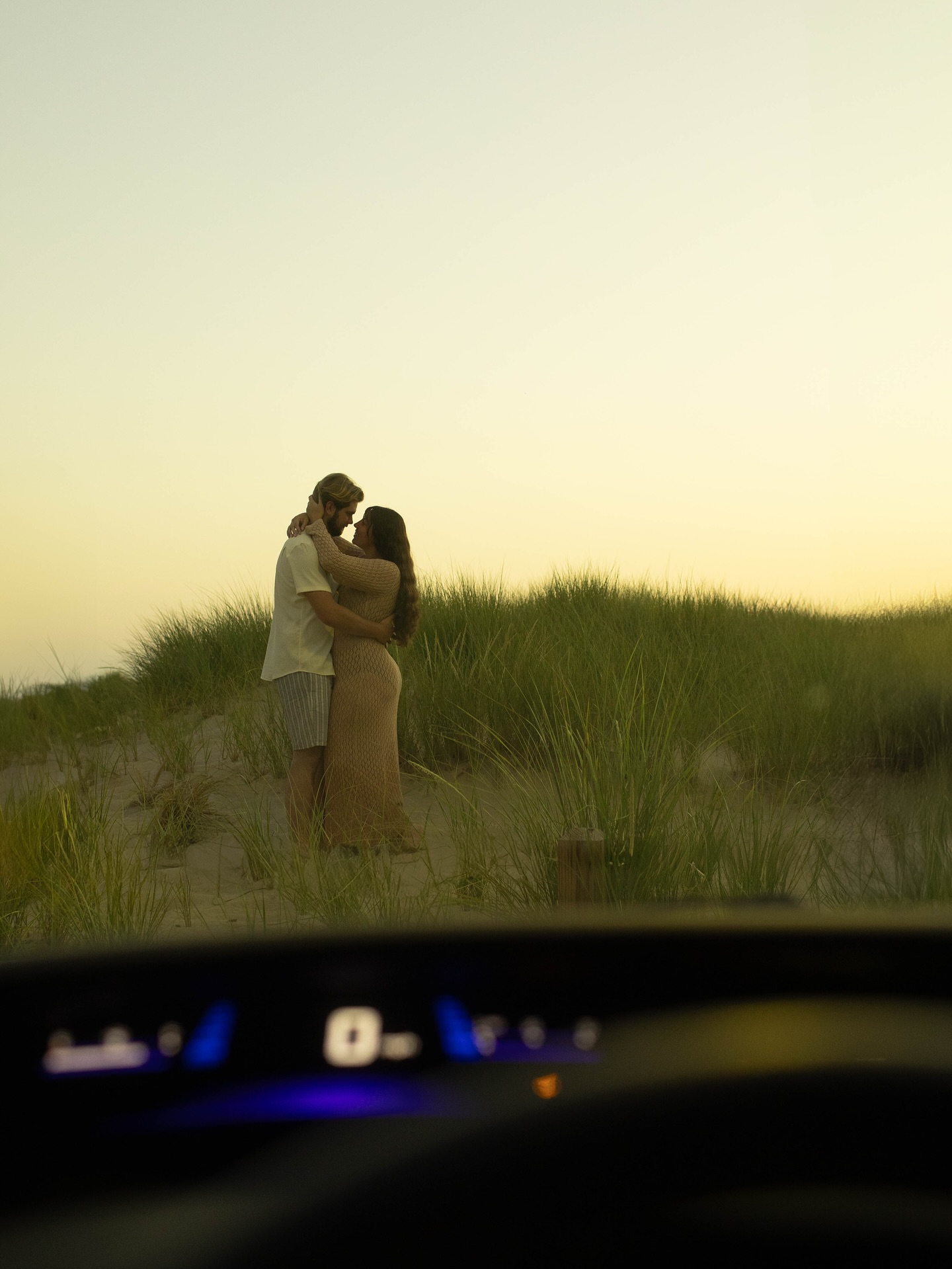 Framing changes everything…
Same couple. Same light. Same spot.
But do you feel how different these two photos are?
In the first image, I shot through the dashboard lights… it instantly feels like a movie scene. Like you’re tucked in the car, secretly watching this quiet, tender embrace unfold in front of you. That little bit of foreground creates depth and mood.
In the second, I leaned on the car window frame… it’s more literal, more observational. You see the moment, but you also see where we are. The lines and reflections tell you the “place” just as much as the “people.”
Neither is right or wrong… both tell the story differently. That’s the power of intentional framing. It can take one fleeting moment and make it feel cinematic, documentary, or deeply personal… all with just a shift in perspective.
Because photography isn’t just about what you see… it’s about how you see it.