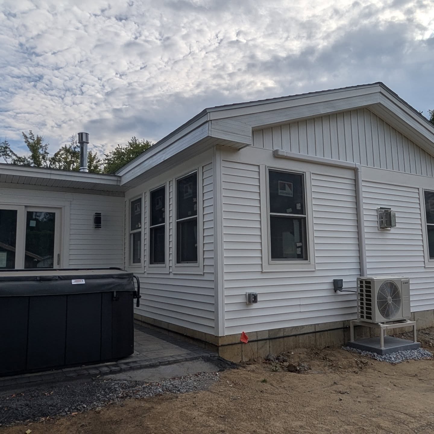 Some exterior photos from our final week of construction. 2 beautiful hand laid patios, 9 new windows, 2 sliders and a combo of lap, board and baton vinyl siding, new hot tub and condenser unit for mini split in the great room.