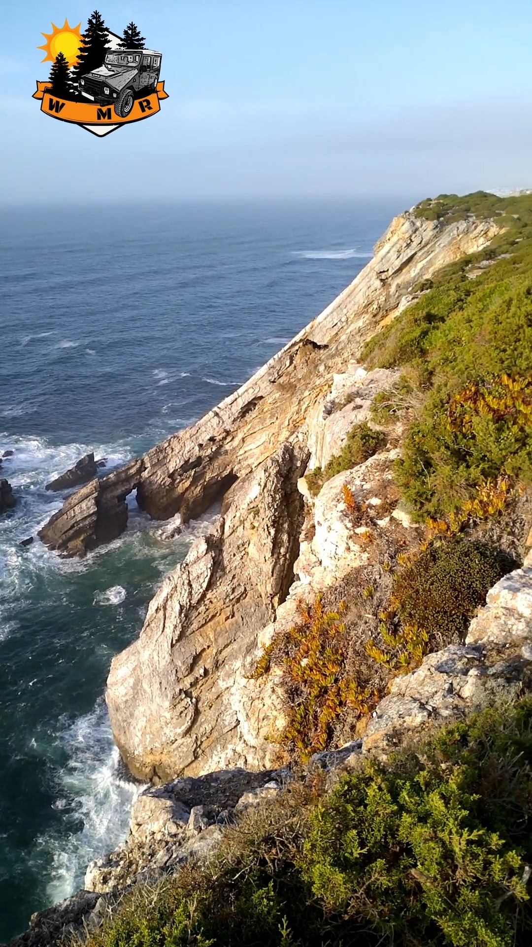 The nearly vertical coastal cliffs of this beach are primarily composed of Upper Jurassic limestones, dating back approximately 150 million years (My). The numerous isolated rock formations deposited along the cliff base provide evidence of the rapid erosion to which the coast has been subjected. Along the cliffs, various geological faults can be observed, some of which are filled with magmatic material in the form of eruptive dikes.
These cliffs are sparsely colonized by sea fennel and some species of sea lavender, providing shelter for various bird species. The corrosive action of weathering and erosion by rainfall on the limestone layers, especially in the more fractured zones, has created a system of deep vertical fissures and caves – Fojo dos Morcegos being the most spectacular example.
Pedra de Alvidrar is another notable geological feature: a layer of crystalline limestone from the Jurassic period that was almost vertically tilted, pushed and deformed due to the emplacement of the Sintra Igneous Complex over 80 million years ago, and subsequently by tectonic movements affecting the Eurasian plate about 18 million years ago.