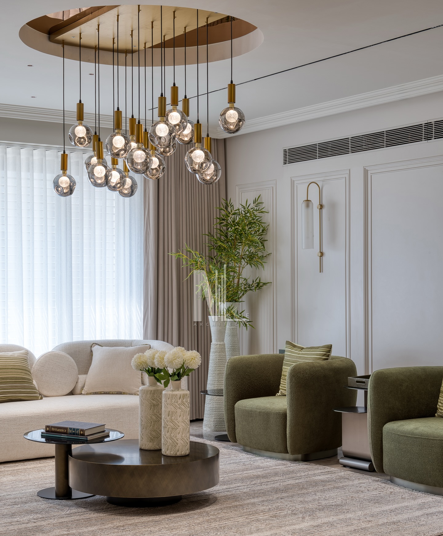 A space where curves, calmness and craftsmanship meet.
From the bespoke 3D flowy wall art to the soft-moulded panelling, every surface carries a sense of movement and quiet luxury. The circular chandelier anchors the room, echoing the rounded sofas, sculptural green armchairs and the low set centre table. Soft sunlight filters through sheer drapes, highlighting layered textures, warm neutrals and subtle brass accents.
A room designed to slow you down, make you breathe, and let the details speak.