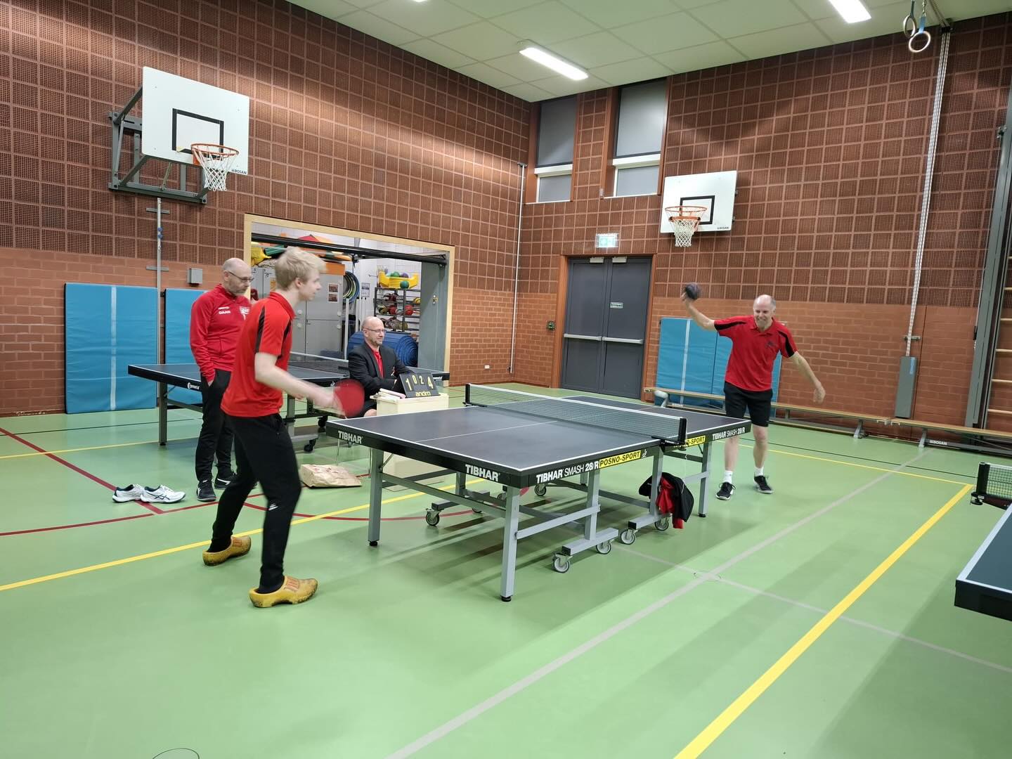Het einde van het jaar is in zicht en dat betekent ook de laatste week tafeltennis bij Zeta in 2025! Dit jaar staat deze week volledig in het teken van onze toptrainer Daan, hij zal in het nieuwe jaar een nieuw avontuur tegemoet gaan.
Dinsdagavond bij zijn laatste seniorentraining kreeg Daan alvast een voorproefje van zijn afscheid wat vrijdag op de planning staat. Het laatste halfuur werd Daan overgenomen als trainer en mocht hij zelf gaan spelen. Tegen iedereen in de zaal werd een wedstrijdje tot de 5 gespeeld. Om het voor Daan wat uitdagender te maken kreeg hij verschillende attributen aangereikt, van klompen tot een wazige bril en een chocoladereep om mee te spelen alles om het spannend te houden👓🍫. Onder toeziend oog van een “officiële” NTTB scheidsrechter (die zijn eigen regelboekje had verzonnen om het Daan zo lastig mogelijk te maken) werd het een avond veel plezier en een geslaagde laatste seniorentraining van Daan.
Was je er niet bij? Zorg dan dat je vrijdagavond op de club aanwezig bent. Dan geeft hij zijn laatste jeugdtraining en nemen we officieel afscheid van Daan👋