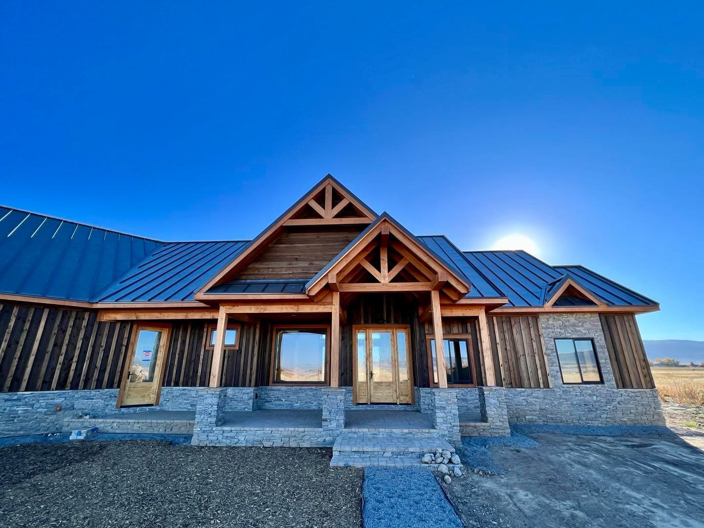Traditional mountain home aesthetics accented by heavy timber entry trusses and beams, rustic board-and-barren siding, and stone veneer.
We build this house in Tetonia off-grid utilizing a solar trailer. Utilizing our double-stud wall system, triple-pane windows, air/tight detailing, and a heavy blanket of cellulose insulation in the attic this house requires minimal heating inputs. This house now runs almost exclusively off solar power with a little help from a propane back up heater in the heat-pump system to assist on the shortest and coldest days of the year.
#off-grid #mountainhome #customconstruction #dreamhome #tetonvalley #builtbetter