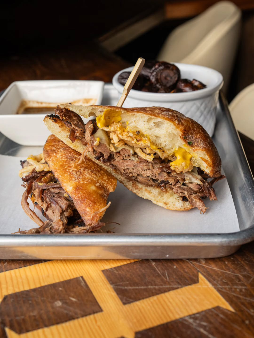 BRISKET DIP | Smoked, pulled brisket, sauteed mushrooms, crispy onions, caramelized onions, gruyere, hot mustard on grilled ciabatta with black garlic jus