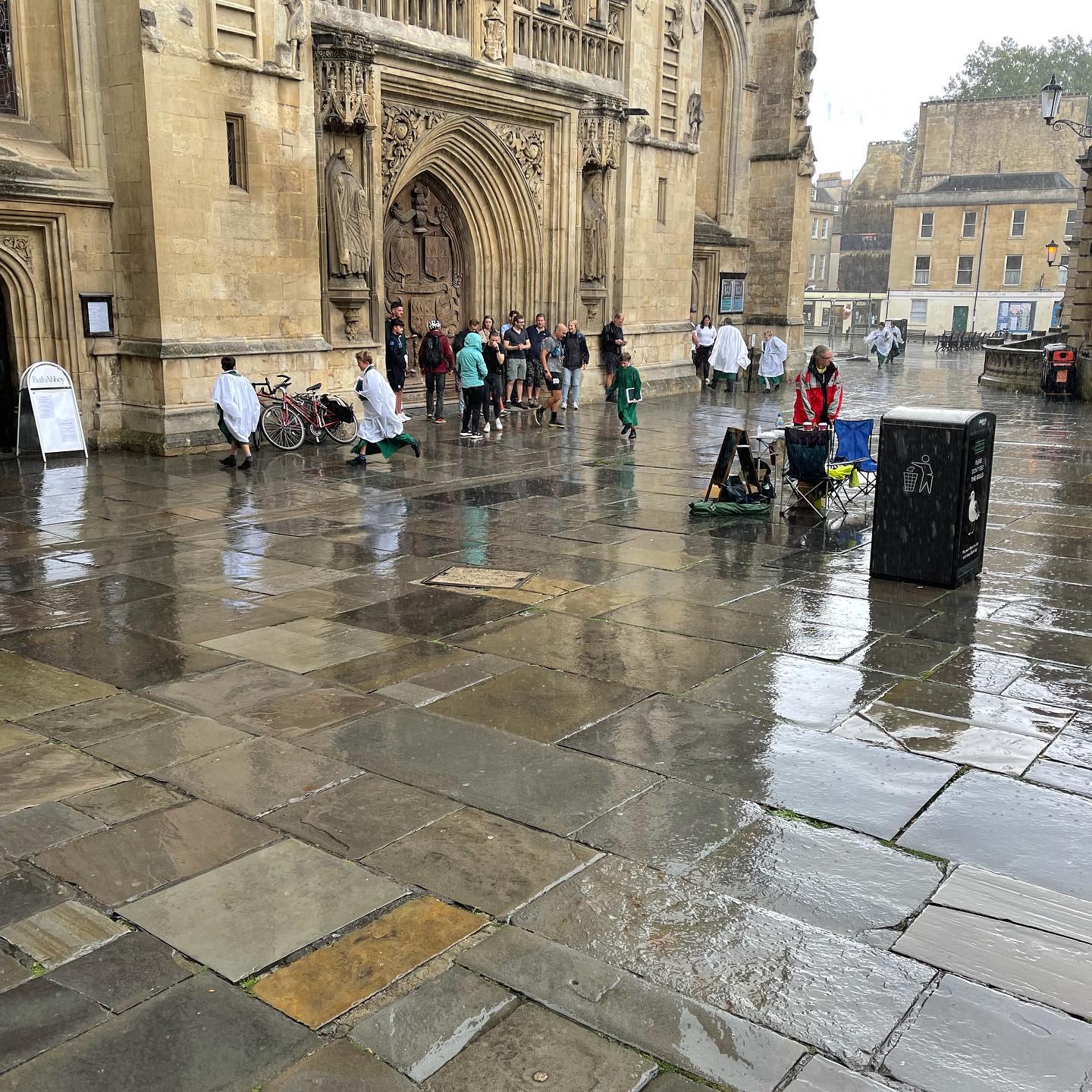 The Bath Abbey choir are running in the rain.