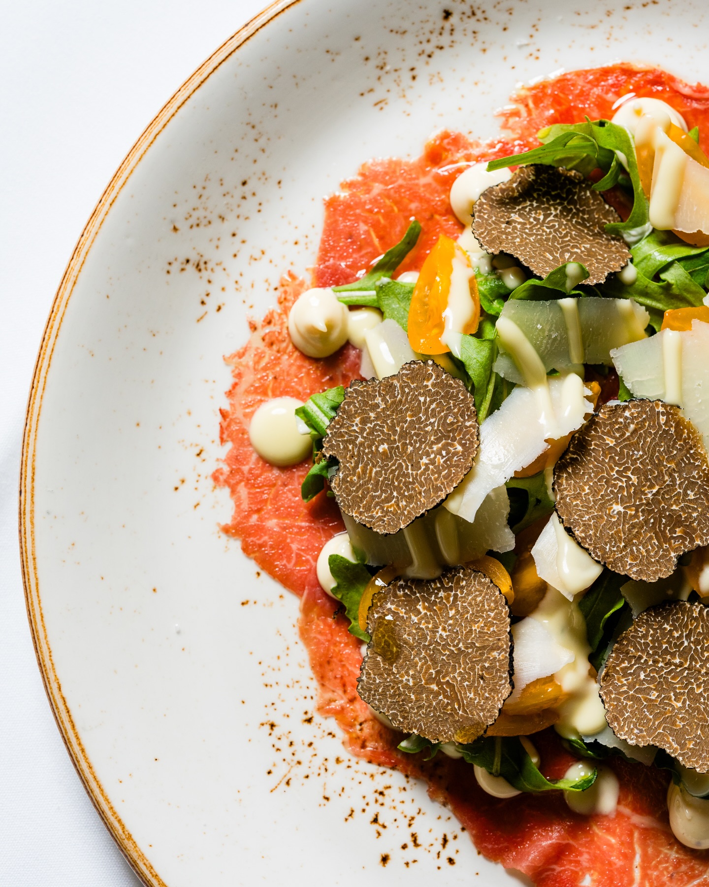 Our Carpaccio di Manzo, delicately sliced beef carpaccio, arugula, 24-month aged Parmigiano, and black truffle.