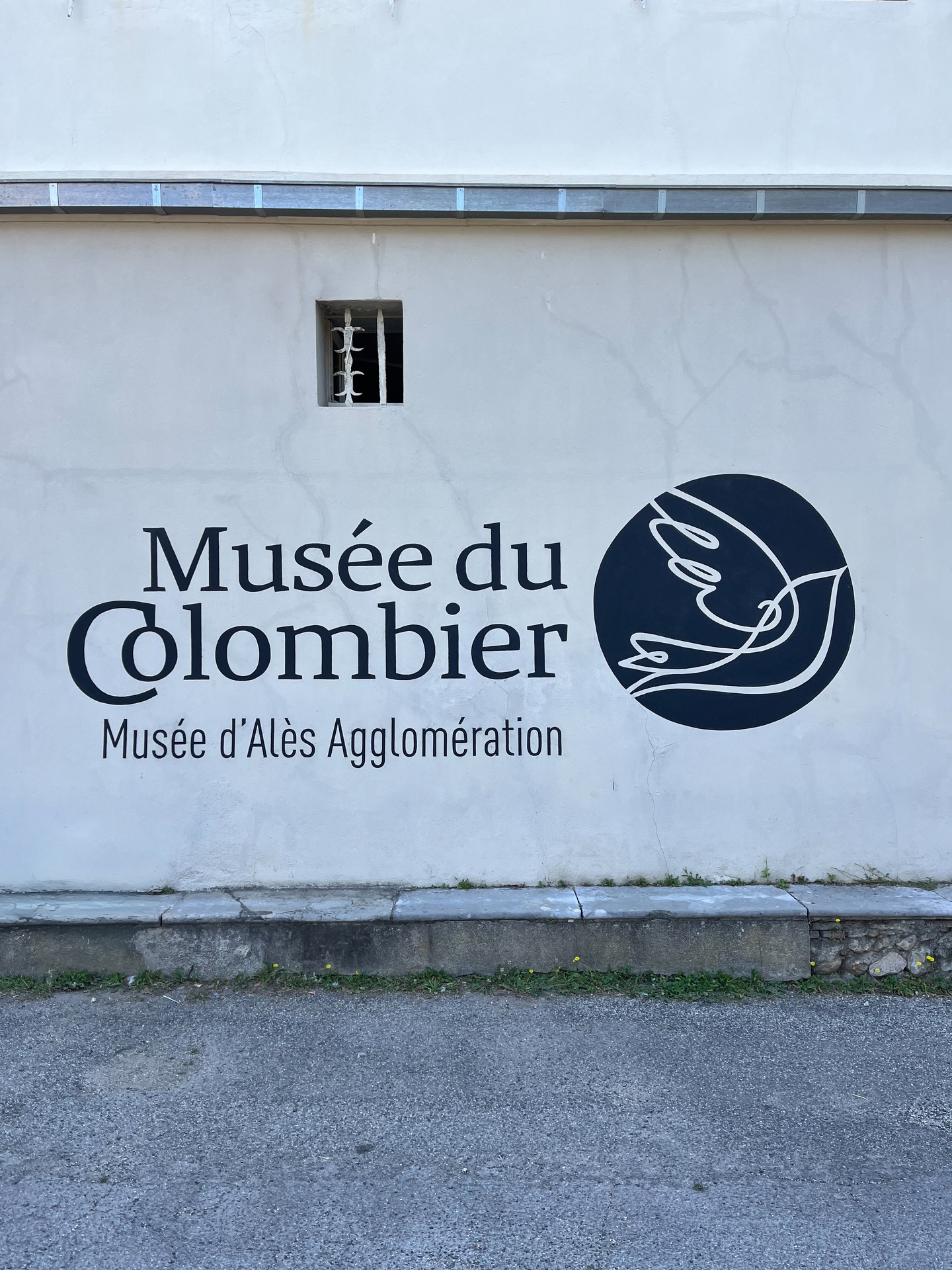 🕊 Réalisation d’une signalétique peinte à la main pour le Musée du Colombier à Alès.
Le lieu souhaitait une signalétique visible à hauteur des yeux, capable d’attirer naturellement le regard, tout en restant en cohérence avec l’architecture et l’histoire du bâtiment.
Dans un édifice ancien, chaque intervention compte. Ajouter un panneau moderne peut parfois créer une rupture visuelle. Peindre directement sur le mur permet au contraire de s’intégrer à la matière existante, de respecter les volumes, les teintes, les aspérités.
Le choix s’est donc porté sur une peinture murale, réalisée dans un esprit sobre et traditionnel. Une solution durable, lisible et artisanale, en accord avec l’identité du musée et l’âme du bâtiment.