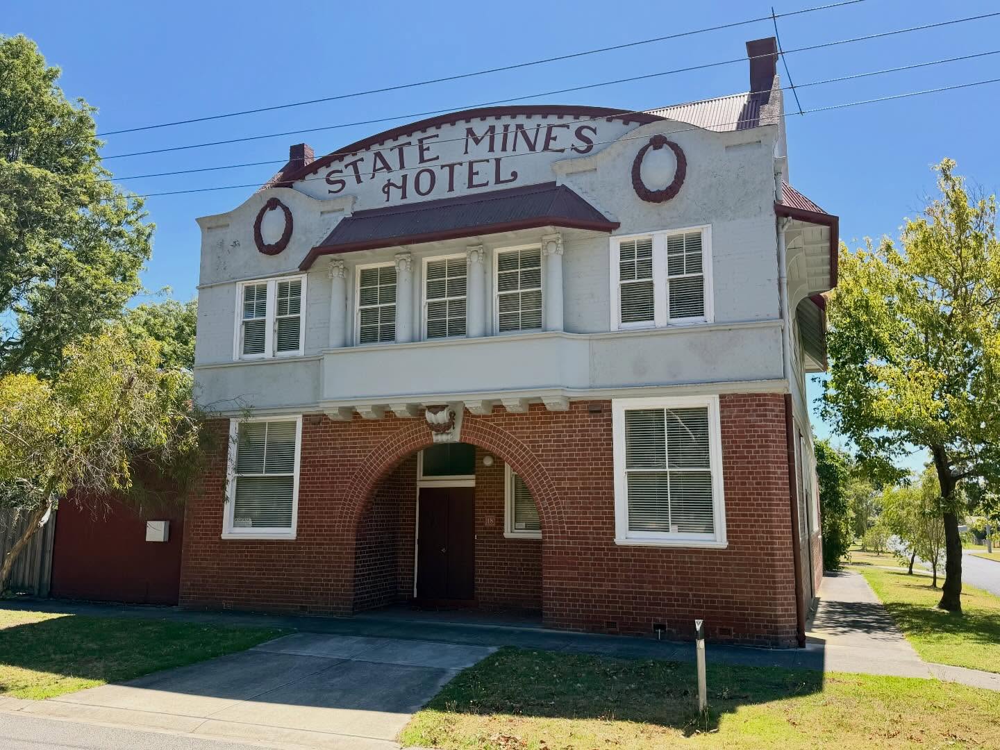 Former State Mines Hotel, South Dudley (HO74, Bass Coast), built c. 1915. Another fieldwork find: a boldly composed Federation Free/Edwardian Baroque hotel, built in the orbit of the Wonthaggi State Coal Mine. Very theatrical within a purely residential, very humble setting. A recessed entry arch with an emphatic keystone, modillion brackets at the cornice line, and an upper balcony carried on Ionic columns. The hotel name is flanked by rendered cartouches, with roughcast banding and finer rendered striping enlivening the composition (now partly obscured by overpainting). Arthur H. Fisher, a leading (now I think little-known) Melbourne architect, appears to have been the designer.