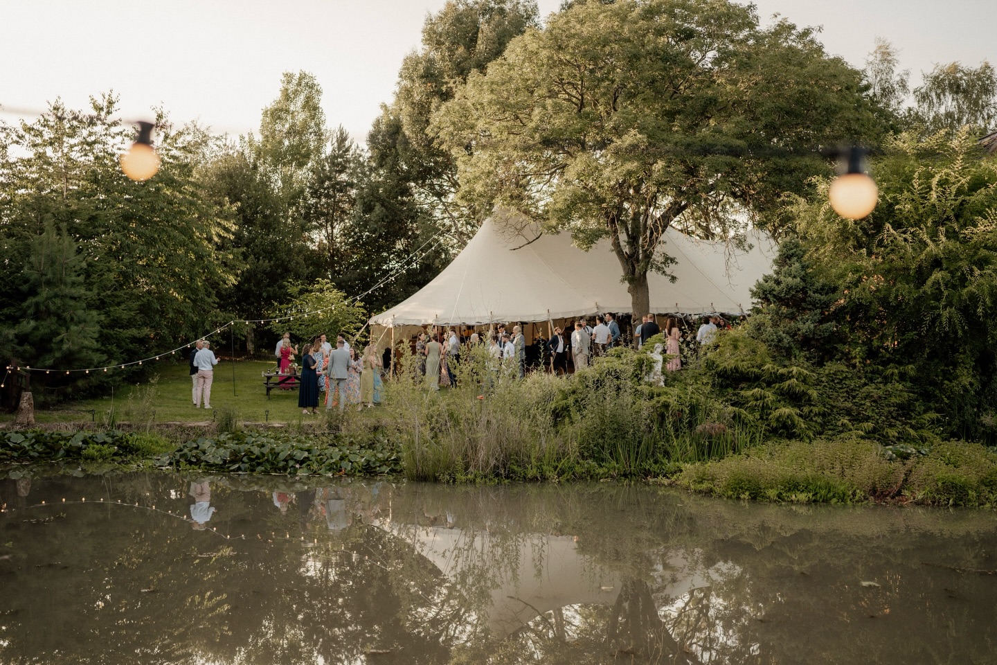 There’s something truly magical about a marquee. By day, it stands beautifully against the landscape! Light-filled, open, and effortlessly elegant. But as dusk begins to fall the real transformation begins.
With the simple flick of a switch, the festoon lights glow, fairy lights begin to twinkle and the whole marquee comes to life. Nestled gently among the trees, it feels almost enchanted.
We can’t not mention the reflection in the water. Shimmering light, doubling the sparkle and creating the most breathtaking backdrop.
That’s the magic of a marquee celebration.
Photographer - @charlottejoplingphoto
#greenfarmmarquees #itsawills