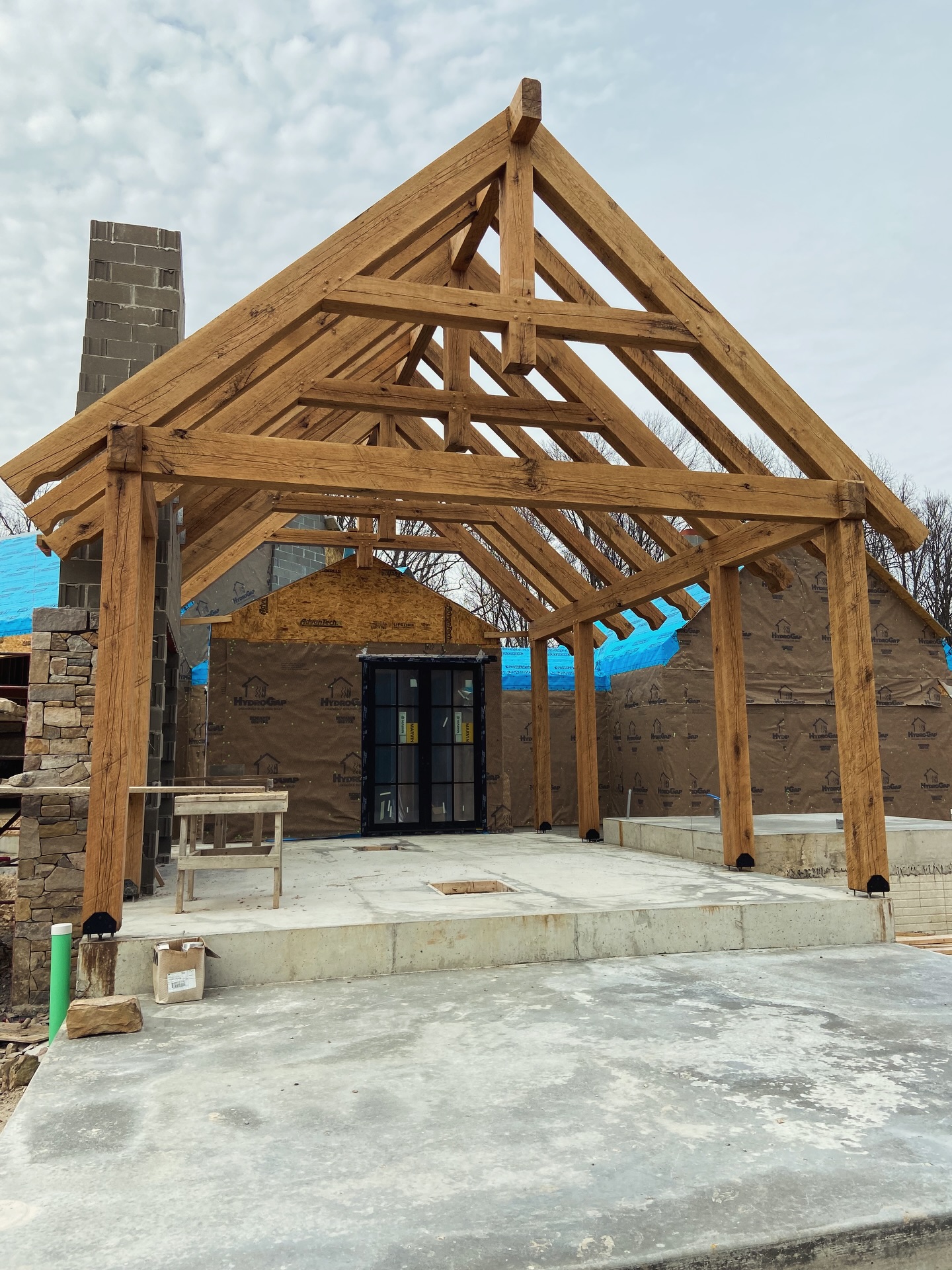 A true timber frame room for all seasons, light capturing monitor, walls almost entirely of glass, arched ceilings and an organization of roofs that create an extraordinary space for entertaining. Taking shape in Hocking Hills. #customhomes #architecturaldesign #architecturedetail #roughframing
