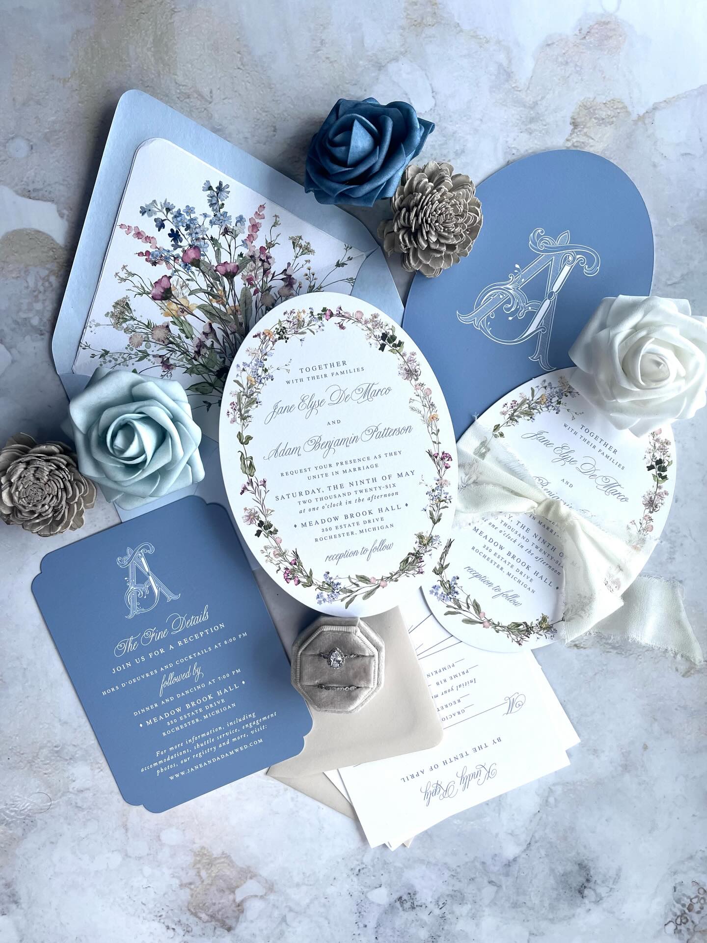 Currently obsessed with oval invitations and specialty cut shapes. They instantly set the tone and make your suite stand out the moment it’s opened.
We partner with a print company that offers a wide range of unique shapes, so you are not limited to the standard rectangle. For digital printing and foil, it is truly the best of both worlds with beautiful detail and a polished finish.
This suite features delicate wildflowers inspired by a French garden, paired with soft and layered blues that bring everything together. The monogram leads the design and carries throughout the entire wedding for a cohesive look.
If you want something that feels elevated and a little unexpected, this is it.