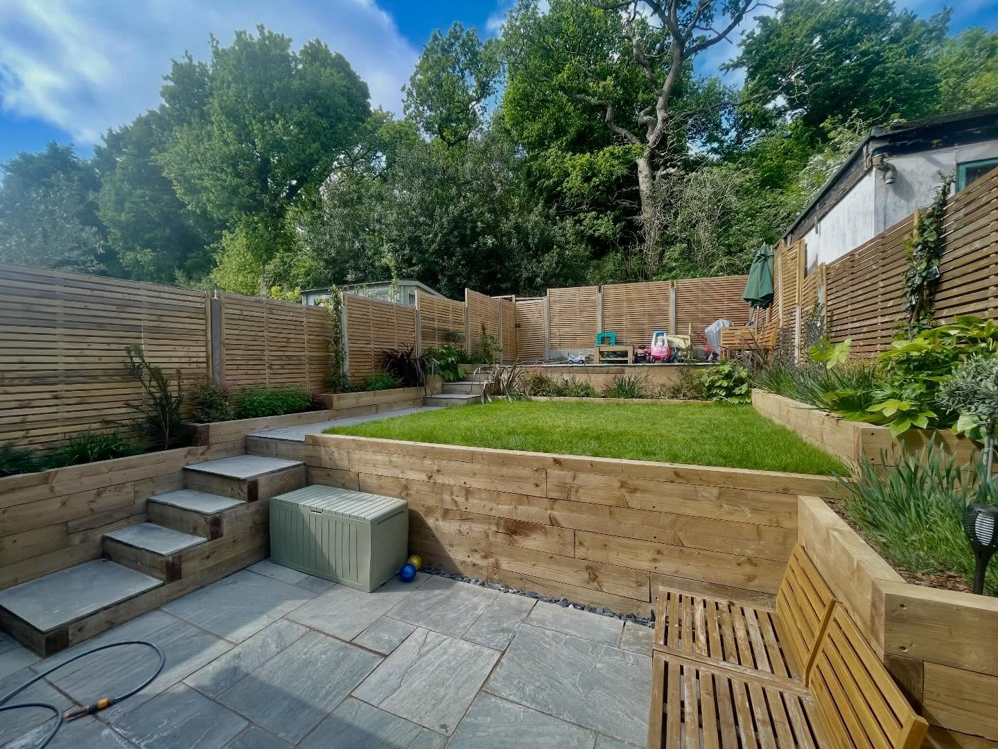 A multi level garden backing onto a forest with severe drainage issues and spaces that weren’t properly usable. The lower level was cut back to give a courtyard style patio with new raised beds throughout for lots of planting to add colour throughout. #raisedflowerbeds #paving #plants #bees #butterflies
