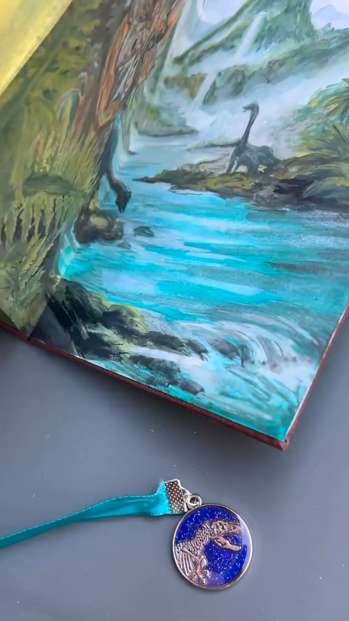 The process of my omnibus (combining multiple volumes) rebinding #JurassicPark and #TheLostWorld - inspired by recent travels to Universal, my epic 2025 reading of the original novels, and of course my childhood obsession with the films. The bookmark charm is a mood stone from a few weeks ago at @amnh. The monstera leaf/glow in the dark raptor eye motif was inspired by a @loungefly bag and I actually made my own raptor eye glow using @mooncat nail polish over my gouache painted endpapers. Peep the little mosquito as the pupil 👌🏻 it’s all in the details. 🦖🦕🗻🌱