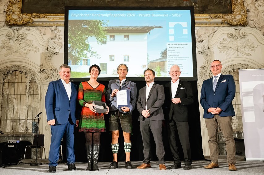 Bayerischer Denkmalpflegepreis 2024 für unser Projekt Mühlgasse 12.
Am 19.09.2024 verlieh Staatsminister Christian Bernreiter unserem Projekt den Bayerischen Denkmalpflegepreis in Silber in der Kategorie private Bauwerke.
In Zusammenarbeit mit dem Bayerischen Landesamt für Denkmalpflege hat die Bayerische Ingenieurekammer-Bau im Oktober 2023 bereits zum neunten Mal den Bayerischen Denkmalpflegepreis ausgelobt. Dieser Preis, der seit 2008 alle zwei Jahre vergeben wird, würdigt das vorbildliche Engagement privater und öffentlicher Bauherren, gelungene Bauwerke und die dabei eingebrachten Leistungen der Ingenieure verschiedenster Fachrichtungen. Die eingereichten Projekte zeigen durchweg ein beachtliches Niveau beim Umgang mit Denkmälern.
Die zahlreichen Einreichungen verdeutlichen darüber hinaus die Vielfalt baulicher Denkmäler in allen bayerischen Regierungsbezirken. Die Jury war angetan von der Ausführungsqualität und der guten Präsentation aller Projekte. In den Kategorien »Öffentliche Bauwerke« und »Private Bauwerke« wurden jeweils drei Preise vergeben.
Fotos 1+2: Tobias Hase
Fotos 3+4: Stefan Müller-Naumann
#denkmalschutz #landkreisgarmischpartenkirchen #holzbau #architektur #bauenmitholz #bayern #badheilbrunn #architekturbüro #denkmalpflege #architekturdesign #holzdesign #holzarchitektur #bauenimbestand #holzbauimdenkmalschutz #architekturbayern #oberland #baukultur #newbavarianarchitecture #baukulturregionvoralpenland #bavarianarchitecture #archtecture #architekten #badtölz #garmischpartenkirchen #weilheim #schongau #miesbach #lebenbauenbewegen #bayikbau