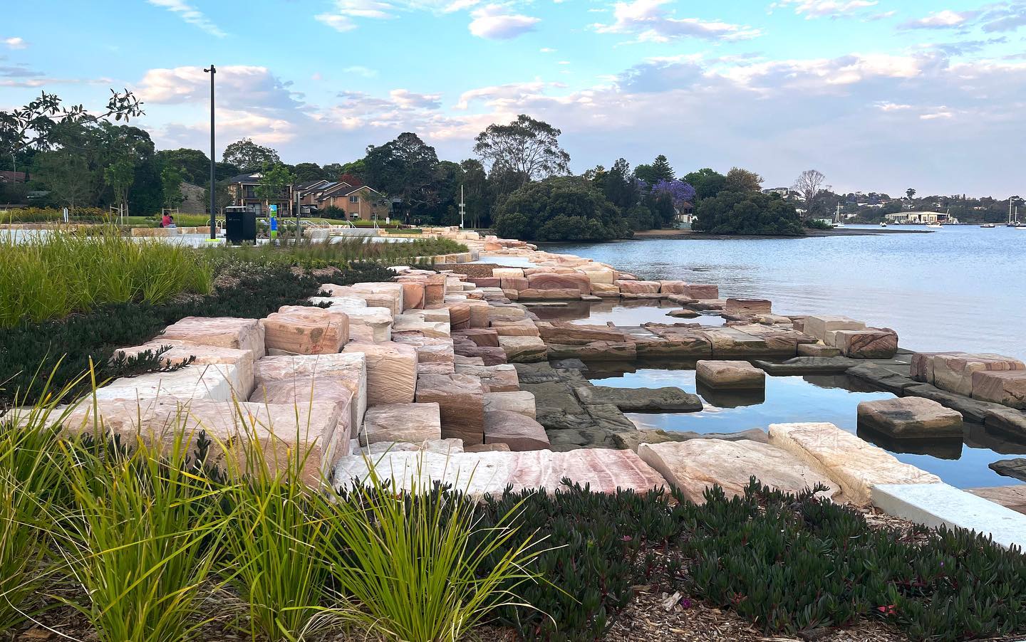 McIlwaine Park’s biophilic focused design allows the user to feel emersed in the natural surroundings of Brays Bay. It gives the visitor an up close and personal interaction with the bay, it’s water movements and marine life. Originally flagged as a potential swim site for the Parramatta River this project has strived to connect people to the waters edge. When the ongoing challenges of water quality precluded for the medium term future the inclusion of swimming opportunities, the design focused in on maintaining the water connection in a diverse number of ways. The design maintains flexibility which will allow adaption into a future swim site as the river water quality improves further.
The park also contributes to improving the health of the bay by providing protective habitat at the water’s edge. By transforming a 107m section of the original 1970s seawall into a natural informal character, the rockpools, salt marsh and living seawall tiles, integrated into the intertidal zone, encourage a diversity of marine life to help strengthen the rivers ecosystem.
McIlwaine Park provides an inclusive destination for the growing population of Rhodes, engaging the community with the river and its changing faces. We are excited to see this park open, and look forward to following its further evolution. @canadabay @tonkinteam @glascott_landscape