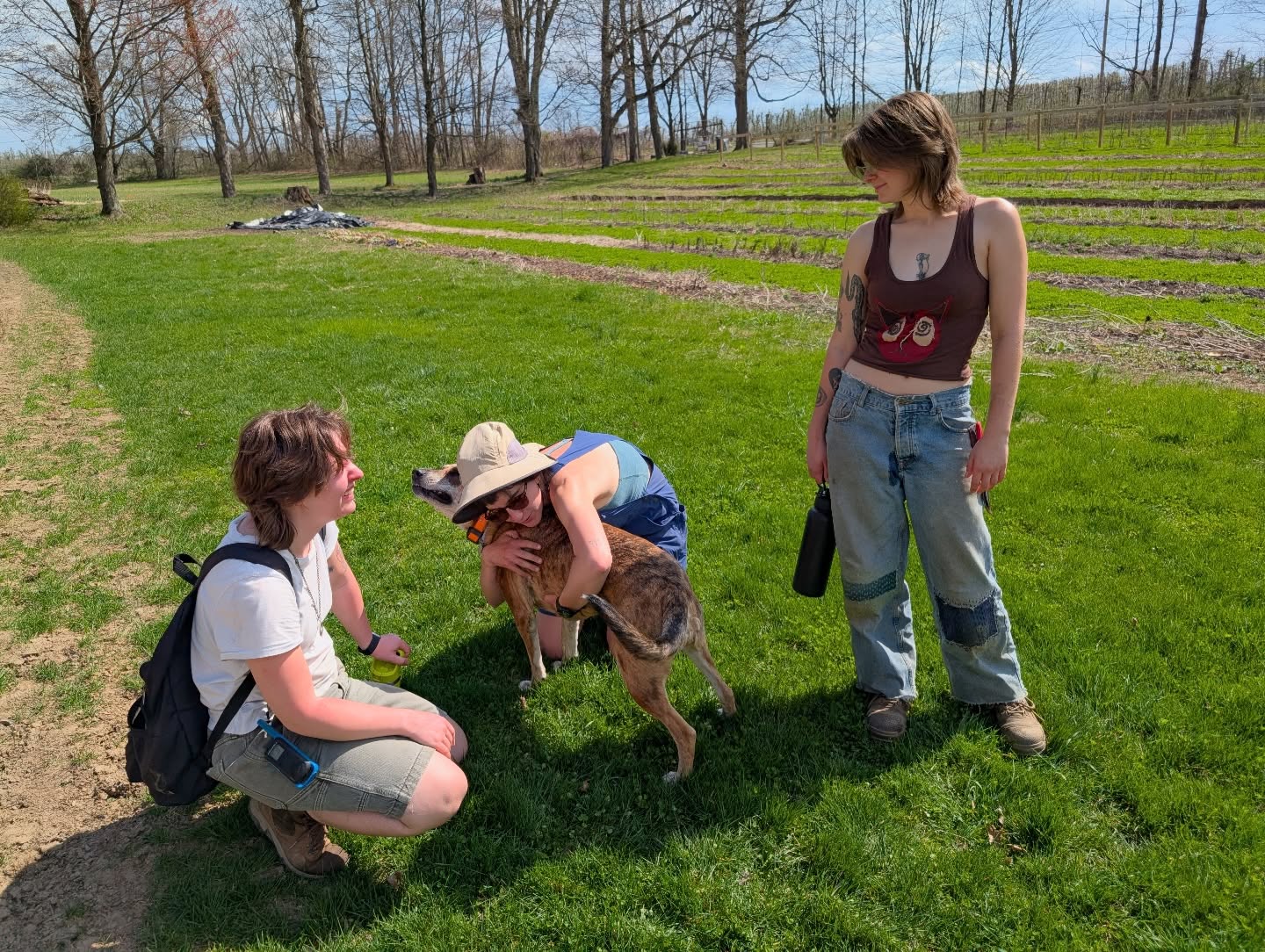 During a quick break, Farm Apprentices Michele and Izzy learned the most important lesson of the day from Assistant Farm Manager Haidee: how to give Farm Dog Amelia hugs.