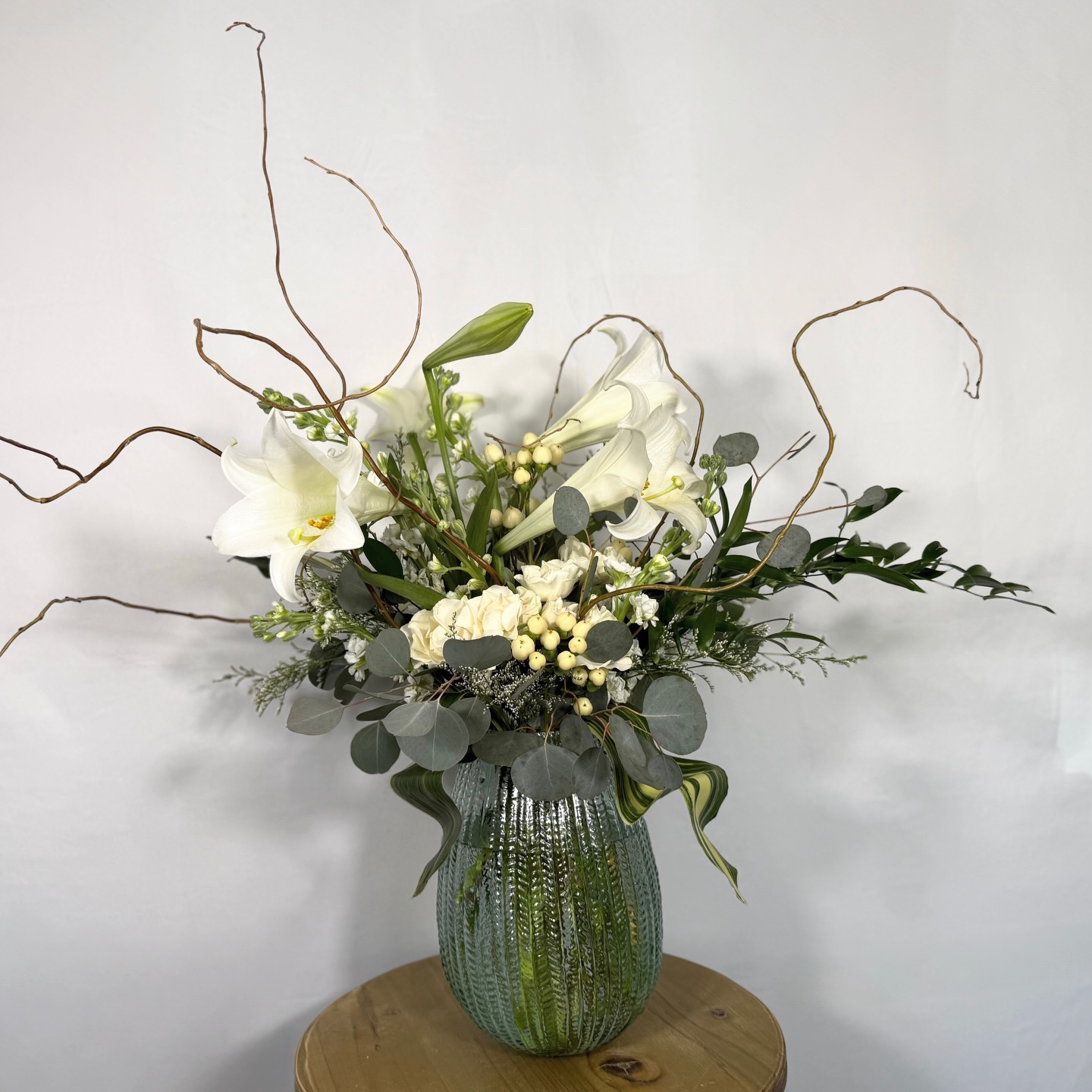 Bursting out of a textured, spring kissed glass vase, these stunning Easter lilies are the true stars bold, elegant, and full of that fresh Easter magic. Twirling curly willow branches add a playful bounce, while silver dollar eucalyptus, white spray roses, and hypericum berries bring in that soft, whimsical charm.
It’s bright, it’s joyful, and it’s basically Easter in bloom flowerbar style! #Easter #flowers #love #magic
