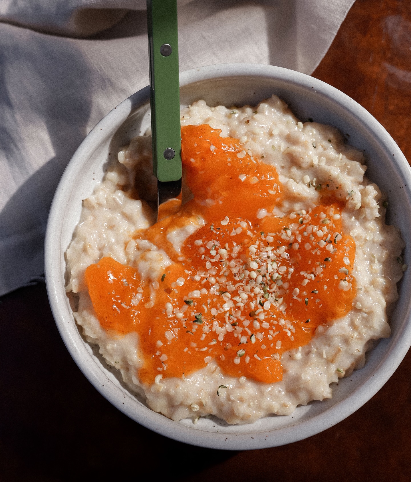 A cosy bowl of cardamom porridge topped with jammy persimmon and nutty hemp seeds. On repeat.
