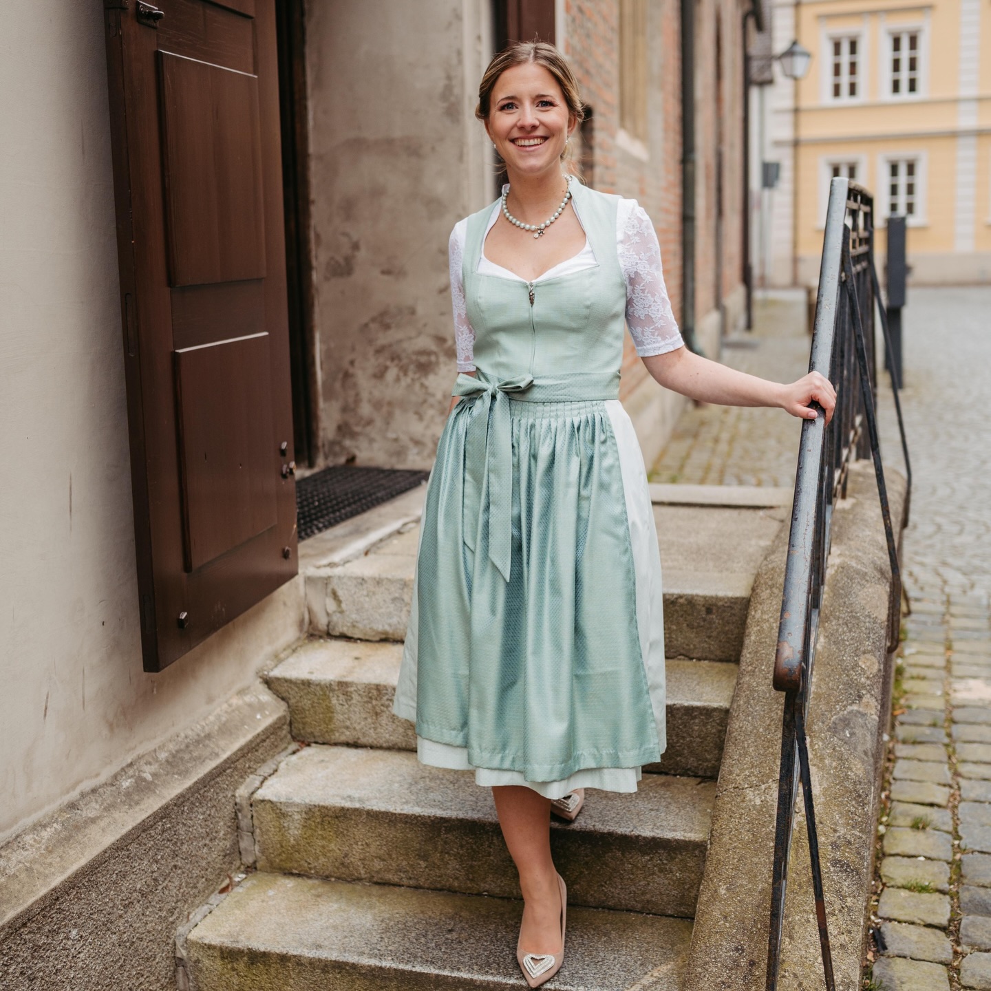 Wir freuen uns, euch heute ein ganz besonderes Highlight unserer Kollektion vorstellen zu dürfen: Unser Dirndl Ramona.
Es besticht durch das klassische Leinenoberteil, das durch den außergewöhnlichen Ausschnitt und den eleganten Stehkragen eine besonders edle Note erhält. Die feine Zierpaspel am Ausschnitt unterstreicht die hochwertige Verarbeitung, auf die wir bei uns im Haus so viel Wert legen.
Kombiniert wird das Mieder mit einem 70 cm langen Rock aus dezent bedruckter Baumwolle, der durch die gelegten Falten eine wunderschöne, feminine Silhouette zaubert. Die harmonisch abgestimmte Jacquard-Schürze rundet den hellen, sommerlichen Look perfekt ab.
Unser Tipp: Ramona ist durch ihre hellen Farbtöne der ideale Begleiter für festliche Anlässe und warme Tage.
Da man die Struktur des Leinens und den perfekten Fall des Rocks am besten live erlebt, laden wir euch herzlich zur Anprobe bei uns im Laden ein. Wir freuen uns darauf, euch persönlich zu beraten!