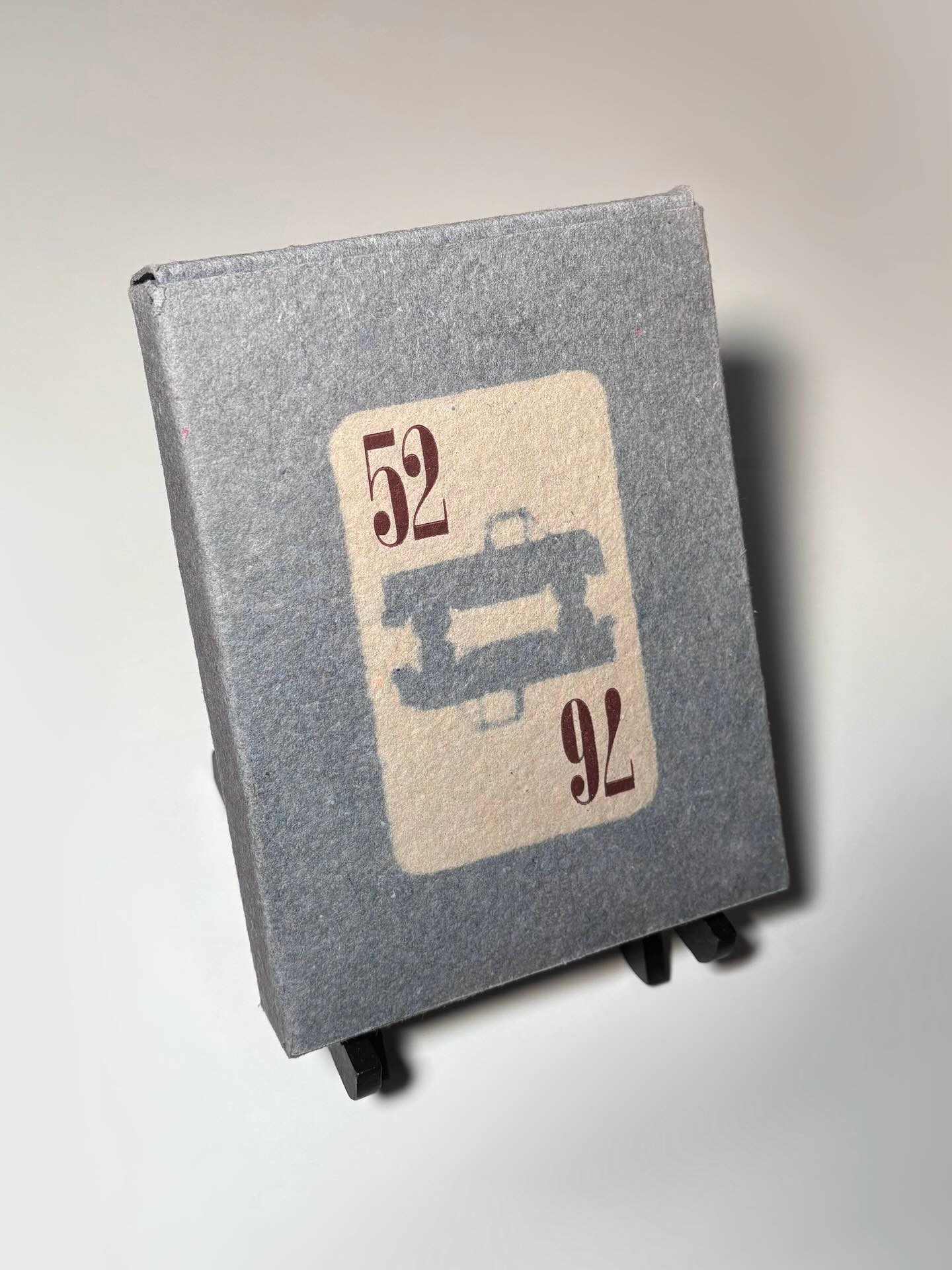Today I’d like to focus on the box itself that is home to the 52 Pickup 76 collection. I really enjoy the denim effect of the handmade paper box and how the numbers are printed so crisply against it, I think it creates a nice contrast with the muddled lines. The inspiration behind the title is also made quite clear with the use of the card face and the shape of the box. I also love that “pickup” in the title takes on two meanings with this packaging, both referring to the card game and the truck images that mirror each other on the card face. On top of all this, all 52 poems, including the title page, end matter and specifications sheet perfectly inside this custom made packaging.