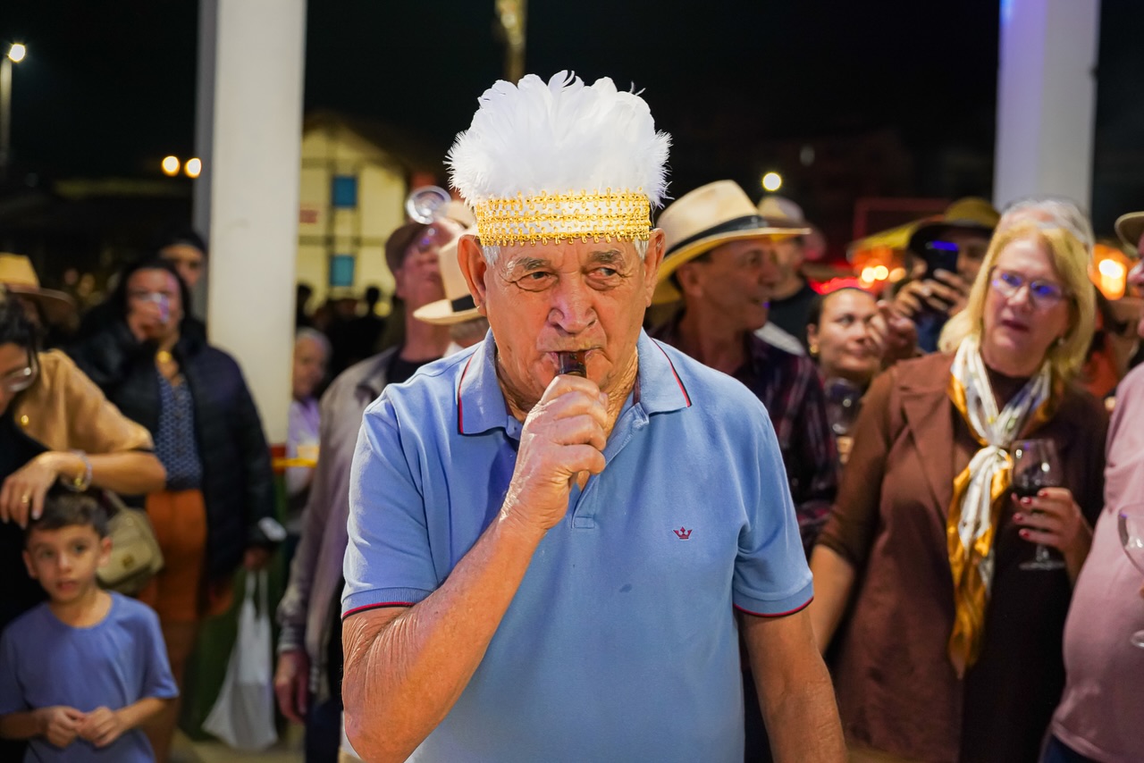 Um dos momentos mais tradicionais e aguardados do Tempo do Nunca Mais é o protocolo do evento, uma homenagem carregada de significado ao saudoso Padre Cleto, que ajudou a construir e eternizar essa história tão especial para Venda Nova do Imigrante. 🌾🍷🎶
Neste ano, a escolha do cacique aconteceu de uma forma ainda mais emocionante e simbólica: o título foi entregue à pessoa mais velha presente na festa, representando a sabedoria, a memória e as histórias que atravessam gerações.
O Cacique nomeado foi Tirso Altoe que com mais de 80 anos foi coroado pela Rainha da Festa da Polenta com um colar muito semelhante ao oficial utilizado pelo Padre Cleto, tornando esse momento um presente eterno e cheio de significado.
E, mantendo viva a irreverência e o espírito alegre dessa tradição, o homenageado recebeu com carinho o nome de “Cacique Teimoso”.
A partir deste ano, a tradição continuará: o título será sempre entregue à pessoa de maior idade presente no Tempo do Nunca Mais, valorizando aqueles que carregam viva a memória e as raízes do nosso povo.
Um momento marcado por emoção, risadas e pelo respeito às gerações que ajudaram a construir essa linda história.