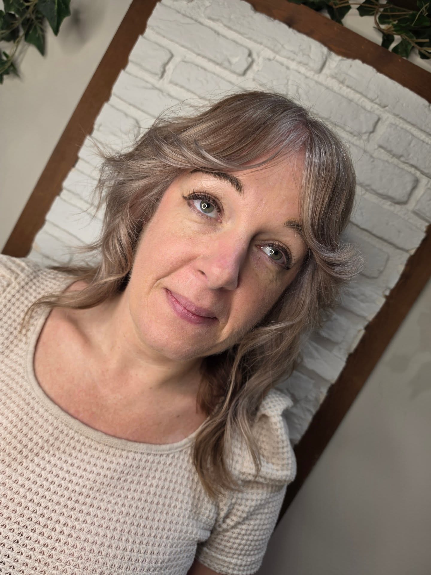 S I L V E R // S O F T E N I N G
Rae and her long-time Stalker are never strangers to a big transformation moment, and this visit marked the beginning of a very different kind of hair journey… embracing the sparkles.
Going grey is rarely just about hair. There’s often a real psychological shift that comes with it too, especially when you’re only 40 and navigating that strange middle ground of still wanting to feel expressive, modern and “you”, whilst also no longer wanting the constant battle of covering every silver that appears.
Instead of fighting against the natural white coming through, Rae and her Stalker decided to lean into it. The previous session (around 4 months ago) was a rich chocolate brunette with blonde highlights, which actually gave us the perfect foundation for beginning the grey blending process.
After a proper consultation and talking through the MANY routes you can take when transitioning softer and lighter, the pair mapped out a plan that felt realistic, wearable and still cool.
Rae carefully grey mapped the natural distribution of silver throughout the hairline, alongside the mousey natural base still sitting through the crown and nape. Around the front, foils were used to lift out previous artificial colour through the mids and ends, bringing them closer to the natural silvers already appearing at the root.
Through the rest of the hair, Rae worked to neutralise lingering warm chocolate and golden tones, softening them into this beautiful taupe-greige shade that blurred the regrowth line and helped everything melt closer towards her natural colour pattern. No colour was applied to the natural root at all!
A global toner then refined the prelightened pieces, cancelling warmth and colour matching those beautiful natural silver ribbons around the face.
Cut-wise, Rae restored her Stalker’s signature flicked fringe and added wolf-inspired layers throughout to create movement, softness and volume without losing length. Finished with a loose lived-in wave for that effortless 70s cool energy.
Would you consider entering your silver disco era?