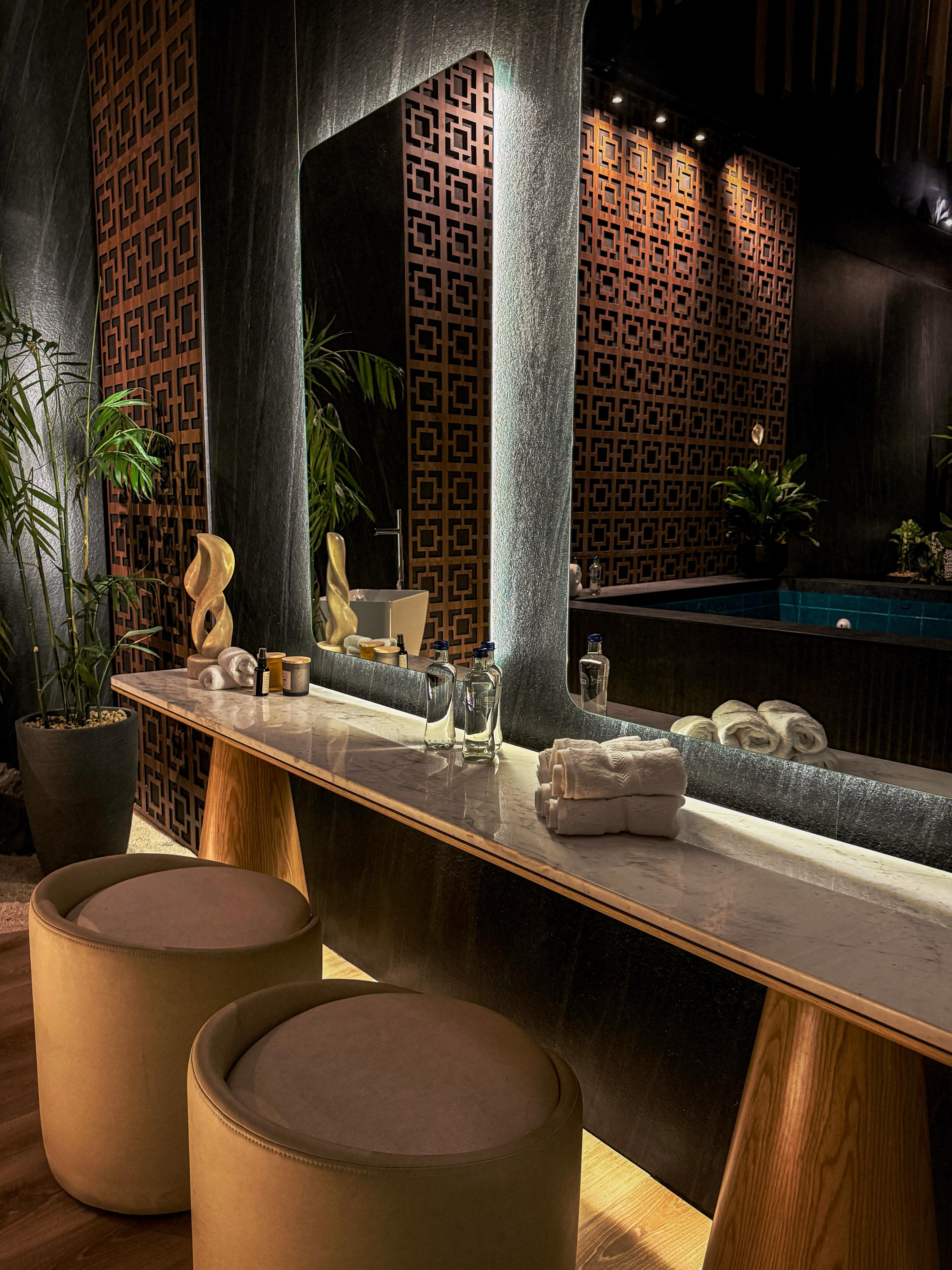 Este spa fusiona la sofisticación contemporánea con una atmósfera de calma absoluta: iluminación indirecta que envuelve el ambiente, texturas que transmiten exclusividad, acabados oscuros que aportan profundidad y una piscina central que se convierte en el protagonista de una experiencia única.
Diseñado por Camila Gos para Casacor Perú 2026, en este proyecto arquitectura, paisajismo y materialidad se integran para crear experiencias que trascienden lo estético y se viven a través de los sentidos.
“El concepto de Alma Wellness Club nace de la tierra, la calma y la energía natural. Cada textura, cada color y cada elemento fue pensado para crear una experiencia sensorial completa. En las áreas de yoga y de skincare, la conchuela bajo los pies rompe con lo convencional y obliga al cuerpo a estar presente, generando una sensación inmediata de grounding y mindfulness”, dice su creadora.
@camilagosdesign
Paisajismo: @pferreropaisajismo
Conchuela en el área de yoga y skincare: @conchuelaperu
Escultura encima del tocador: Ananta, de @conchuelaperu