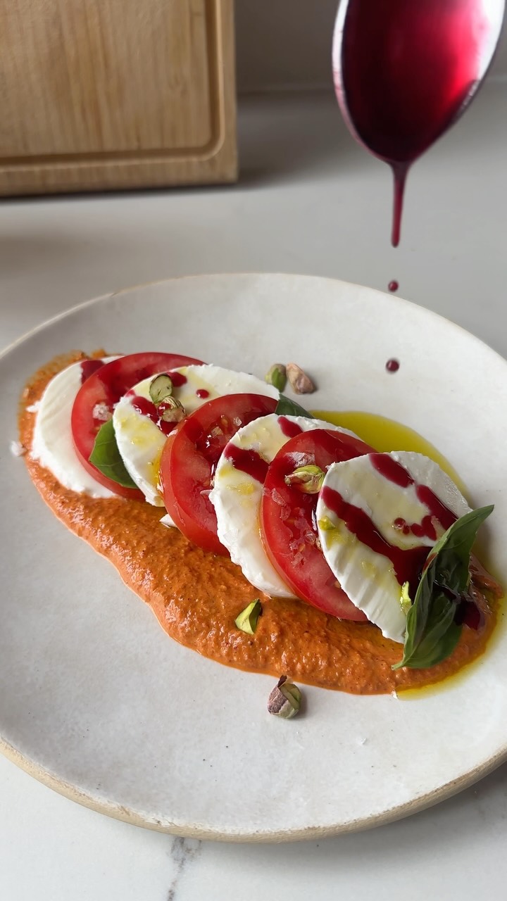 PECAN-LIME MUHAMMARA CAPRESE
Fresh mozz goes with so many things, including delicious, tangy Muhamarra! The creamy rich cheese plays well against the tangy, pomegranate- and citrus-laced nutty muhamarra dip (adapted from my Sababa cookbook). Juicy tomatoes, basil, a drizzle of grassy olive oil, and some flaky salt make this a perfect little plate.
For the muhamarra:
a 16-ounce jar fire-roasted peppers, drained, rinsed, and patted dry
2/3 cup lightly toasted pecans
2 tablespoons pomegranate molasses, plus more for drizzling
1 tablespoon fresh lime juice, plus more to taste
1 garlic clove, smashed
1 teaspoon ground cumin
1 teaspoon kosher salt, plus more to taste
½ tablespoon chili flakes
⅓ cup olive oil, for drizzling
For serving:
a 4- to 6-ounce ball fresh mozzarella, sliced
1 large, ripe tomato, sliced
Chopped shelled pistachios, for garnish
Basil leaves
Flaky salt for garnish
In a food processor, combine the peppers, pecans, pomegranate molasses, lime juice, garlic, cumin, salt, and chili flakes and process until almost smooth, 30 seconds. With the motor running, drizzle in ¼ cup of the oil until incorporated. Season with more lime juice, pomegranate molasses, and salt to taste.
Spread some of the muhammara on a serving platter and top with alternating slices of mozzarella and tomatoes, adding basil leaves along the way. Garnish with pistachios, drizzle with pomegranate molasses and olive oil, and top with flaky salt.