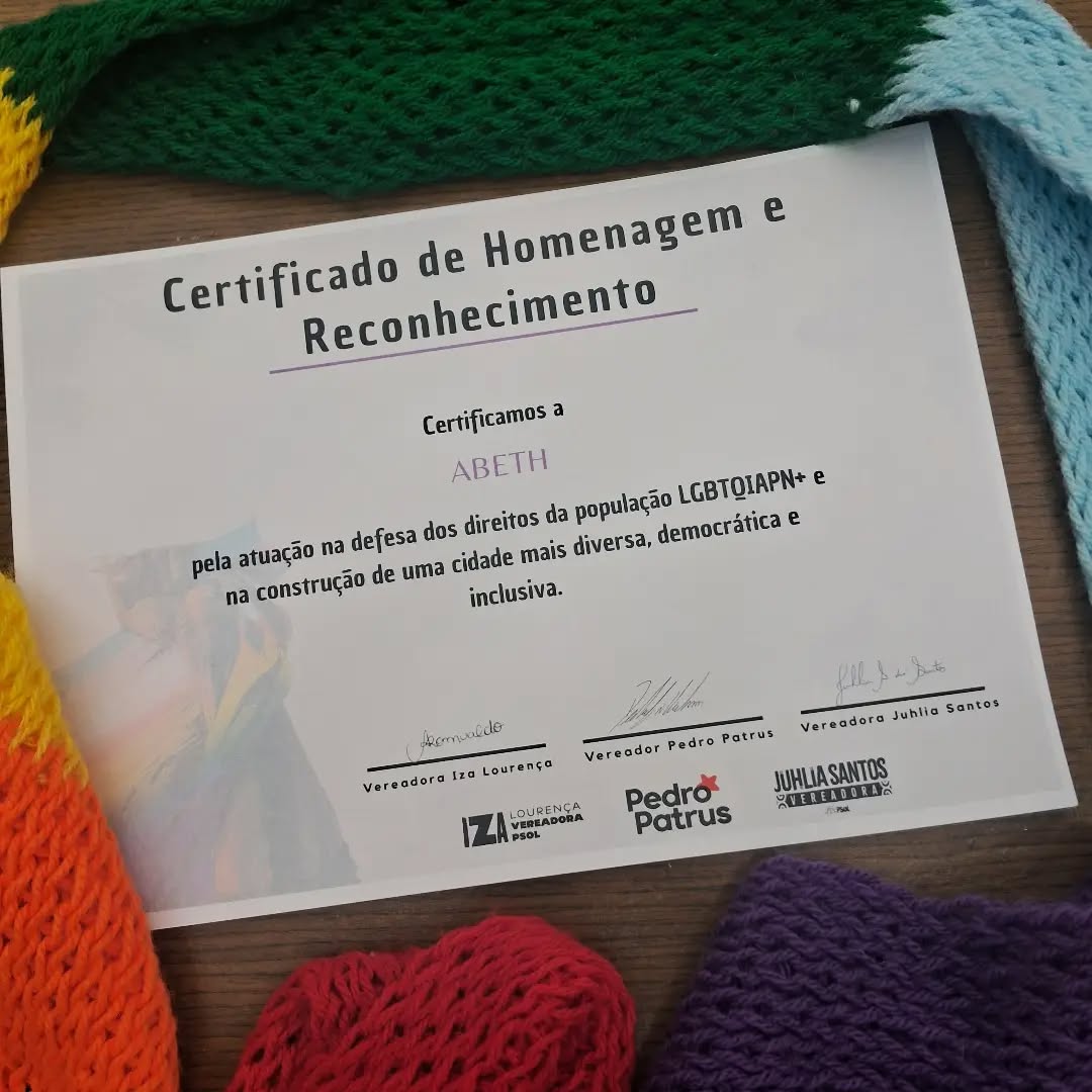 Nesta segunda-feira, dia 22 de junho de 2026, a ABETH foi homenageada na Câmara de Belo Horizonte pelas vereadoras @izalourenca , @juhliasantost e pelo vereador @pedro_patrus .
#PraTodesVerem
Sequência de fotos. 1. Certificado sobre uma mesa de madeira rodeado por uma cachecol nas cores do arco-íris. 2. Na Câmara, Pedro Patrus, Iza Lourença, Catarina Dallapicula segurando o certificado e Juhlia Santos. 3 e 4. Fotografias da entrega do certificado com várias pessoas associadas da ABETH e os vereadores.