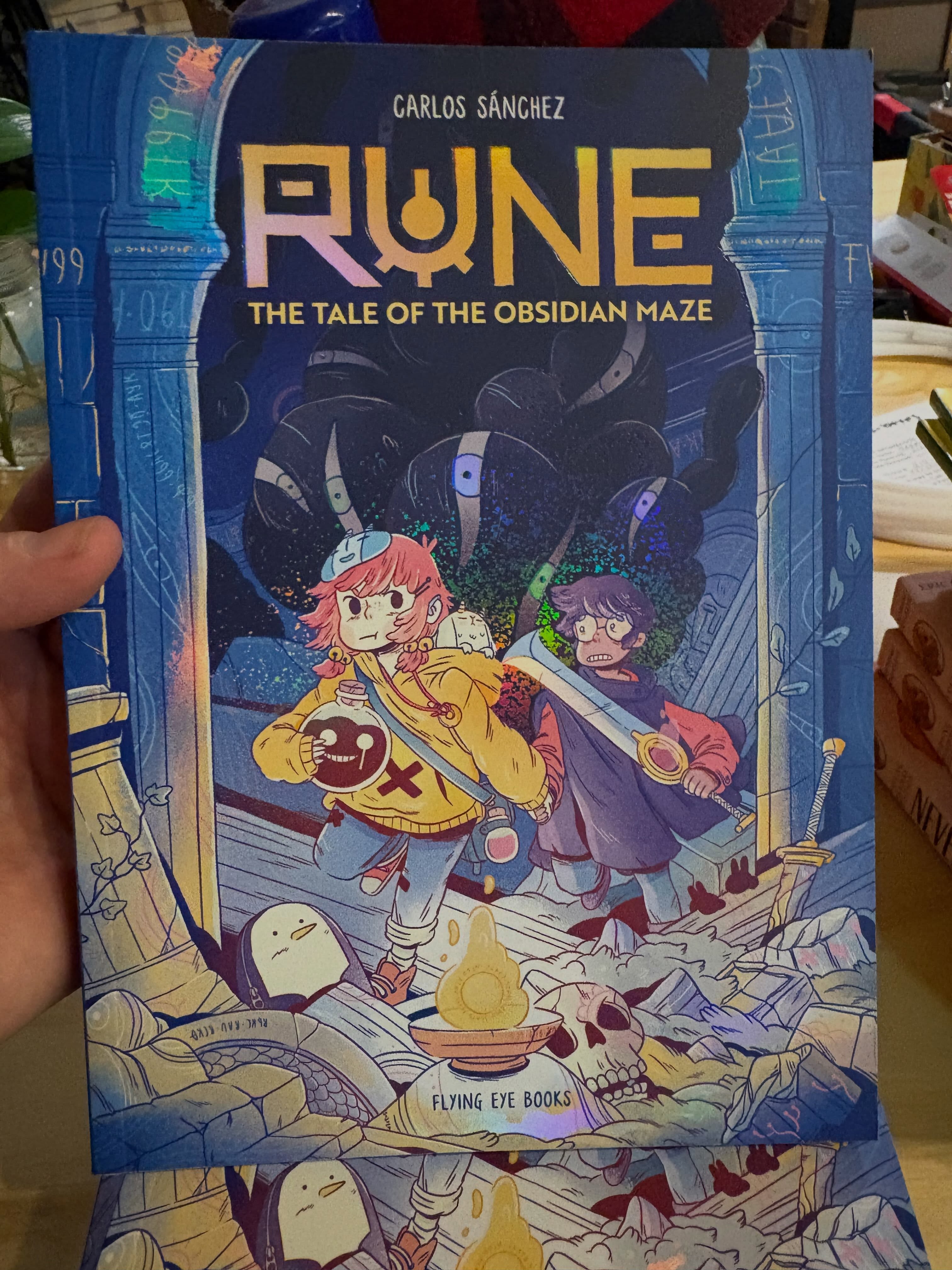 Some of my favorite discoveries for the shop happen when I’m in and I’m so excited that two of the graphic novel series I fell in love with in the UK are finally on our shelves!
Rune by Carlos Sánchez is packed with fantasy, adventure, gorgeous artwork, and a world full of magic and mystery. If you love stories with quests, found family, and unforgettable creatures, this one’s for you.
This is such a beautiful series and perfect for fans of Lightfall and Amulet.
Meesh the Bad Demon by Michelle Lam. This is such a funny, heartfelt, and charming series. It follows Meesh, a demon who would much rather help people than scare them, making it the perfect pick for readers who love humor, heart, and a little bit of magical chaos.