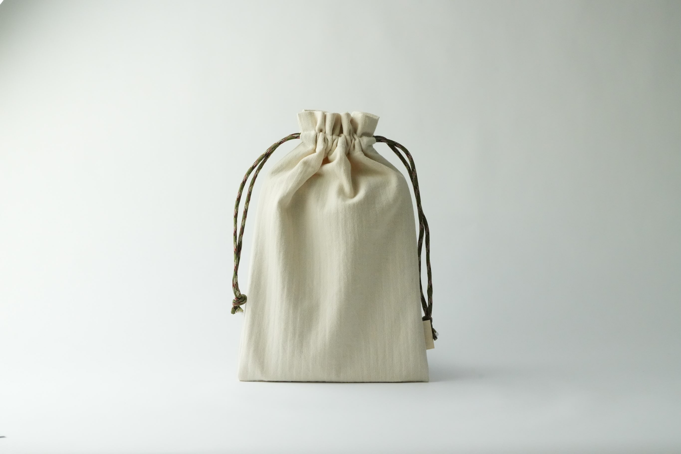 布を持ち歩く生活
コットン100%(縦糸CD20/-、横糸スーピマ10/-)の優しい触り心地が特徴な巾着袋。コットンそのものの色目、キナリの落ち着いたカラートーンになります。ヘリンボン組織にする事で、色々な場面で使う事が出来ます。また持ち手(絞り紐)はキャンプなので使われるカラフルなロープを使用しており、カジュアル使いでも大丈夫。
数量限定にはなりますが、近々販売もスタートしたいと思います。その他にも色々な形も試作中。
引き続き宜しくお願い致します!
#巾着袋 #播州織 #生地