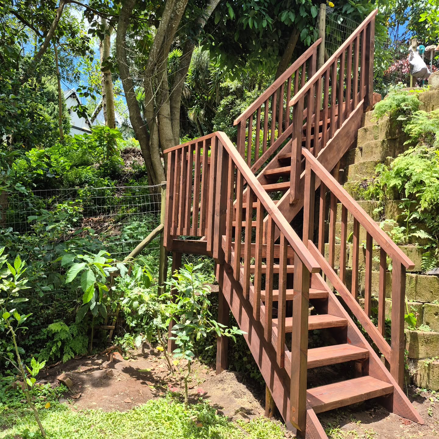 We were brought in to build a comprehensive timber handrail system throughout a residential garden as well as access to an ablutions block - a project that needed to work for two very different sets of needs.
The first set of needs was to create a connecting system of handrails running continuously across multiple levels and garden zones, designed to give a disabled resident steady and consistent grip, and reliable support while moving through their outdoor space. Handrail height and structural integrity were consistent priorities, as the ground beneath shifted from flat path to incline. The handrails and posts were constructed from balau for strength and durability, minimising long-term maintenance requirements.
The second set of needs was for us to build a dedicated stairway to give domestic staff living on site, safe and direct access to the ablutions block on the upper level of the garden. The stairway is CCA treated pine. It was designed with open risers for drainage and ventilation, full balustrades both sides, and all fixings were countersunk and sealed to keep moisture out.
Both the balau and pine were finished with Satinwood 28 sealer for weather resistance while letting the natural grain come through.
📩 If your property needs timber work built around the people who use it, contact us today for an obligation-free quote.
#TimberConstruction #LandscapeJoinery #AccessibleDesign #CustomWoodwork #MistyMountainTimberWorks