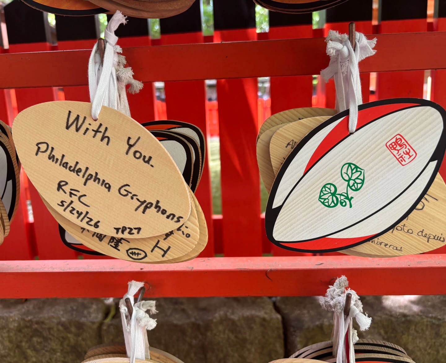 Shimogamo Shrine in Kyoto, Japan contains a subsidiary shrine dedicated solely to Rugby Union.
This dates back to 1910 when the Keio University team (who formed in 1899) came to the Kansai region to teach the sport to their contemporaries at Kyoto University. In order to find a suitable field they came and played at the Shrine. This was the first rugby match to be played by Japanese natives in Kansai.
An engraved boulder remains on site recording the deed and local resident Demi Sakata, who once scored 4 tries against the New Zealand U23 side in 1968, has worked to create a permanent sub-shrine or Sawatasha.
The rugby shrine features a non-traditional Shinto bell in the shape of a rugby ball and visitors are permitted to write and hang wishes on rugby-ball shaped wooden plaques known as Ema.
In 2017 the Shimogamo Shrine was the site of the official draw for the 2019 Rugby World Cup in Japan.
Thanks to a recent visit from Ted the Philly Gryphons are now represented at this UNESCO World Heritage Site! #Rugby #Pride #GrowTheGame