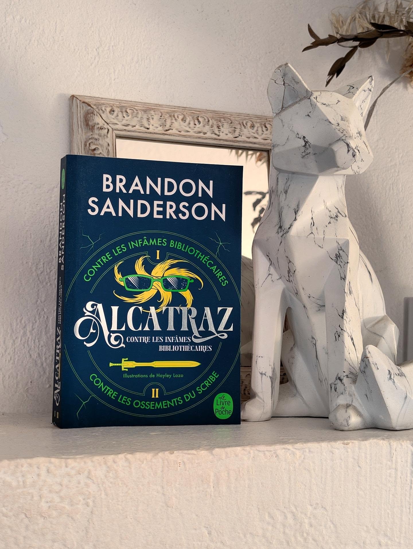 ✨ Alcatraz, tomes 1 & 2 - Brandon Sanderson ✨
Bienvenue dans une aventure complètement loufoque où les Bibliothécaires ne sont pas forcément ceux que vous imaginez...
Je dois dire que je ne savais pas vraiment à quoi m'attendre en commençant cette saga. Et il m'a fallu quelques chapitres pour comprendre dans quoi je m'étais embarqué. Entre les interventions du narrateur, les remarques adressées directement au lecteur et cet humour décalé, le style est vraiment particulier.
Une fois que l'on accepte les règles du jeu, on se laisse finalement porter par cette aventure...
On suit Alcatraz Smedry, un jeune garçon qui découvre qu'il appartient à une famille assez particulière. Forcément, quand votre talent consiste à casser les choses, cela peut sembler inutile... jusqu'à ce que l'on découvre que chaque membre de sa famille possède un talent qui pourrait bien être beaucoup plus important qu'il n'y paraît.
J'ai adoré l'idée de ces pouvoirs qui ressemblent parfois à des défauts. C'est une idée très originale et cela donne lieu à des situations amusantes.
L'univers est très surprenant avec cette guerre contre les Bibliothécaires et ces fameux Royaumes Libres que l'on découvre progressivement. Le deuxième tome permet d'ailleurs d'en apprendre davantage sur ce monde et de développer les personnages que l'on a rencontrés dans le premier.
J'ai particulièrement apprécié Bastille, qui apporte un peu de sérieux à cette équipe qui part régulièrement dans tous les sens. Sa relation avec Alcatraz fonctionne très bien et leurs échanges sont souvent assez drôles.
Je dois tout de même dire que l'humour peut parfois être un peu trop présent et que le style du narrateur m'a demandé un petit temps d'adaptation. Mais c'est aussi ce qui rend cette saga différente des autres.
En bref, c'est une lecture complètement déjantée qui ne plaira peut-être pas à tout le monde, mais qui a le mérite de proposer quelque chose de vraiment original. Pour découvrir le livre, il faut aller voir du côté de chez @livredepoche
#chronique #review #bookstagram #sanderson