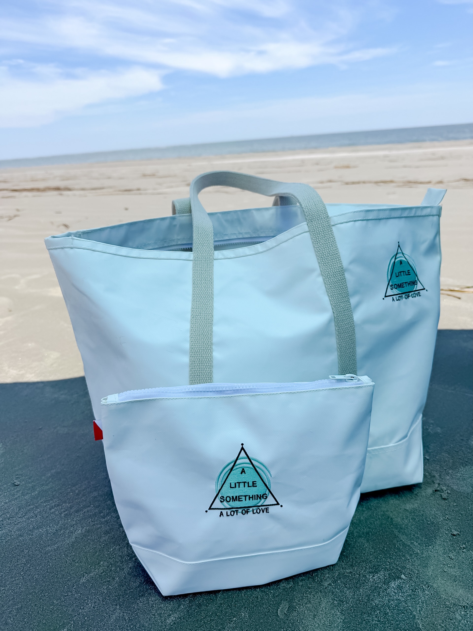 Your @alittlesomethingalotoflove merch is ready and shipping this week! 🩵✨
.
stay tuned for details on local pickup. cannot wait to see where your items take you. these beauties ended up in Charleston, SC! (thanks @gadberrymelissa 😘)
.
thanks so much for your support and don’t forget to tag @alittlesomethingalotoflove and @e.z.embroidery in your new gear 📸🫶🏼
.
.
.
.
#embroiderywork #shorebags #miscarriagesupport #charlestonsc #braceletsinthewild