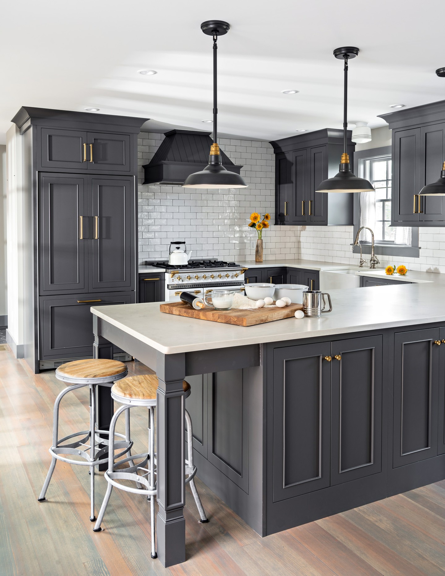 In this Provincetown home renovation, the kitchen finds its character through contrast, craftsmanship, and a carefully layered palette. Deep charcoal cabinetry creates a dramatic foundation, while warm brass hardware, softly reflective tile, and a classic white range bring light and dimension to the room.
The millwork was designed to feel architectural rather than simply functional. Floor-to-ceiling cabinetry maximizes storage, glass-front doors introduce moments of display, and integrated wine storage adds a tailored detail. The custom range hood and substantial crown molding complete the composition, giving the renovated kitchen a sense of permanence within the home.
Viewed through the dining room’s glass doors, the kitchen feels both refined and welcoming—a space designed for everyday Cape Cod living and gathering in Provincetown.
#Provincetown #CapeCodInteriors #CustomCabinetry #ArchitecturalMillwork #KitchenRenovation #InteriorDetails #CapeCodHomes #CapeAssociates
