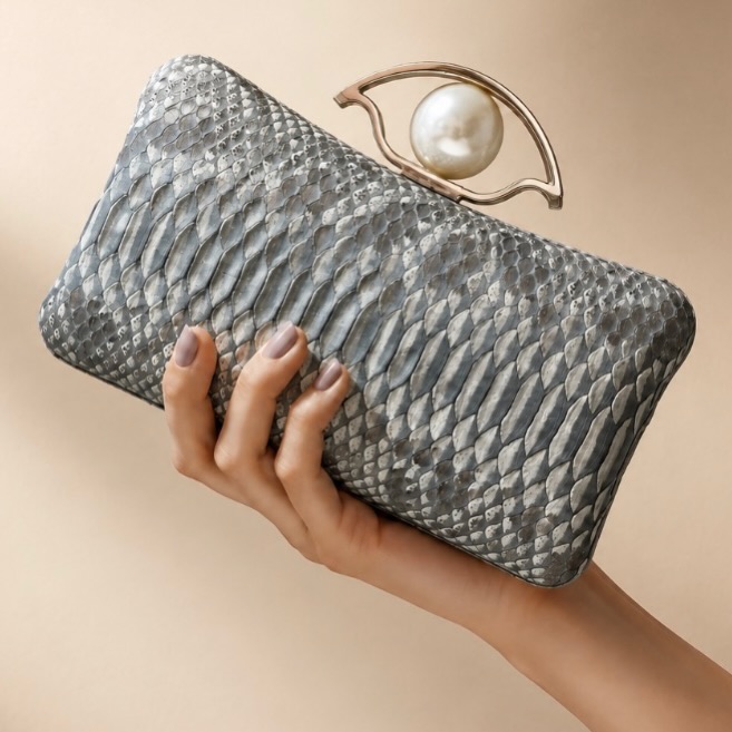 A symbol of protection, reimagined as wearable art. ✨ This one-of-a-kind Evil Eye Pearl Minaudière is handcrafted in genuine python and finished with a luminous pearl detail—an unforgettable statement piece made for today’s goddess.