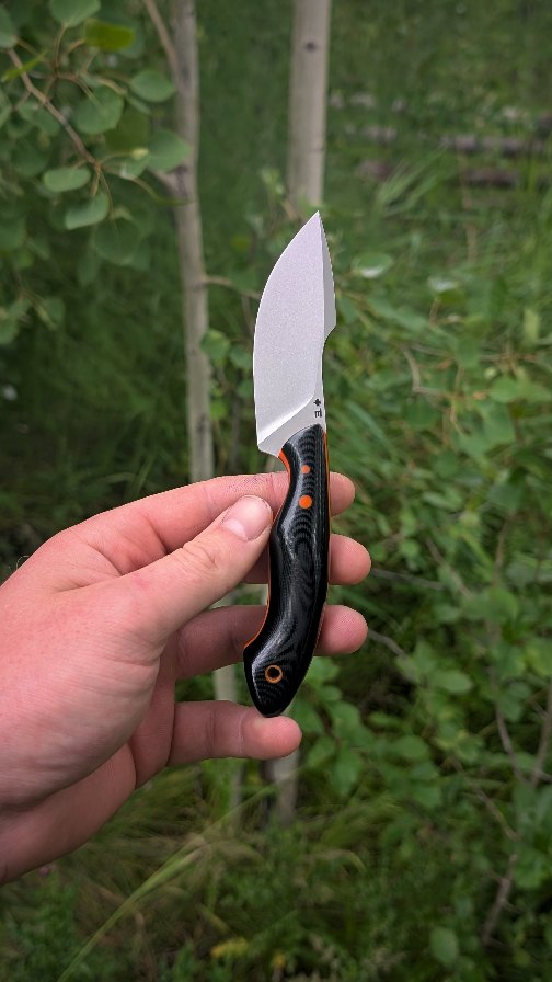 When an order came in for a custom Mesa Mini with a Nessmuk style of blade with exotic materials, I wanted to make one out of simpler materials first to make sure everything was comfortable before I cut into hundreds of dollars of materials. Perhaps this can be the Nesa Mini - Nessmuk Mesa Mini?
Just because it's "simpler" materials doesn't mean it gets a "rough and rugged" or poor finish. It still gets the attention to detail and the very fine polish to show off the grain within the G10. The double liners also add to the black-orange colourway and jazz it up a little bit.
The blade is ground to a thin 8 thou edge and with the ramp on the spine, give your thumb a comfortable place to rest or for your index finger to rest near the tip when making pull cuts.
Just because it's made for use doesn't mean it can't be beautiful.
Statistics.
Style: Nesa Mini
Steel: NitroV
HRc: ≈62
Overall length: 7"
Blade length: 3"
Cutting edge: 2 7/8"
Stock: 3/32"
Handle: Black G10
Liner: Orange & Black G10
Pins: G10
Tube: G10
As always, every step from profiling, to heat treat, to polishing, to leather work is all done myself in Northern BC, Canada.
