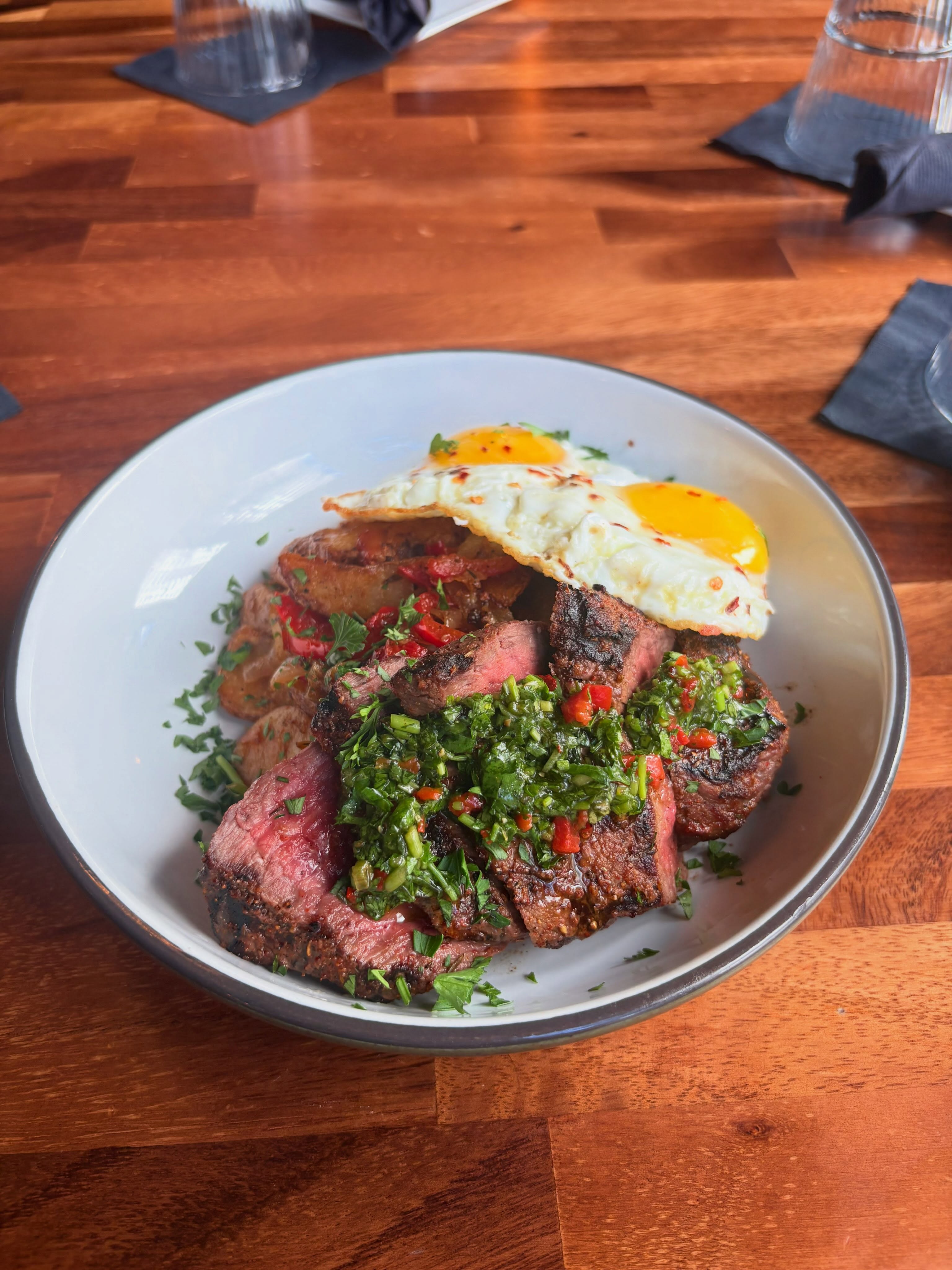 SWEET & SAVORY STEAK & EGGS
Top sirloin drizzled with chimichurri, served over crispy breakfast potatoes with sautéed onions and bell peppers, topped with two sunny-side-up eggs.