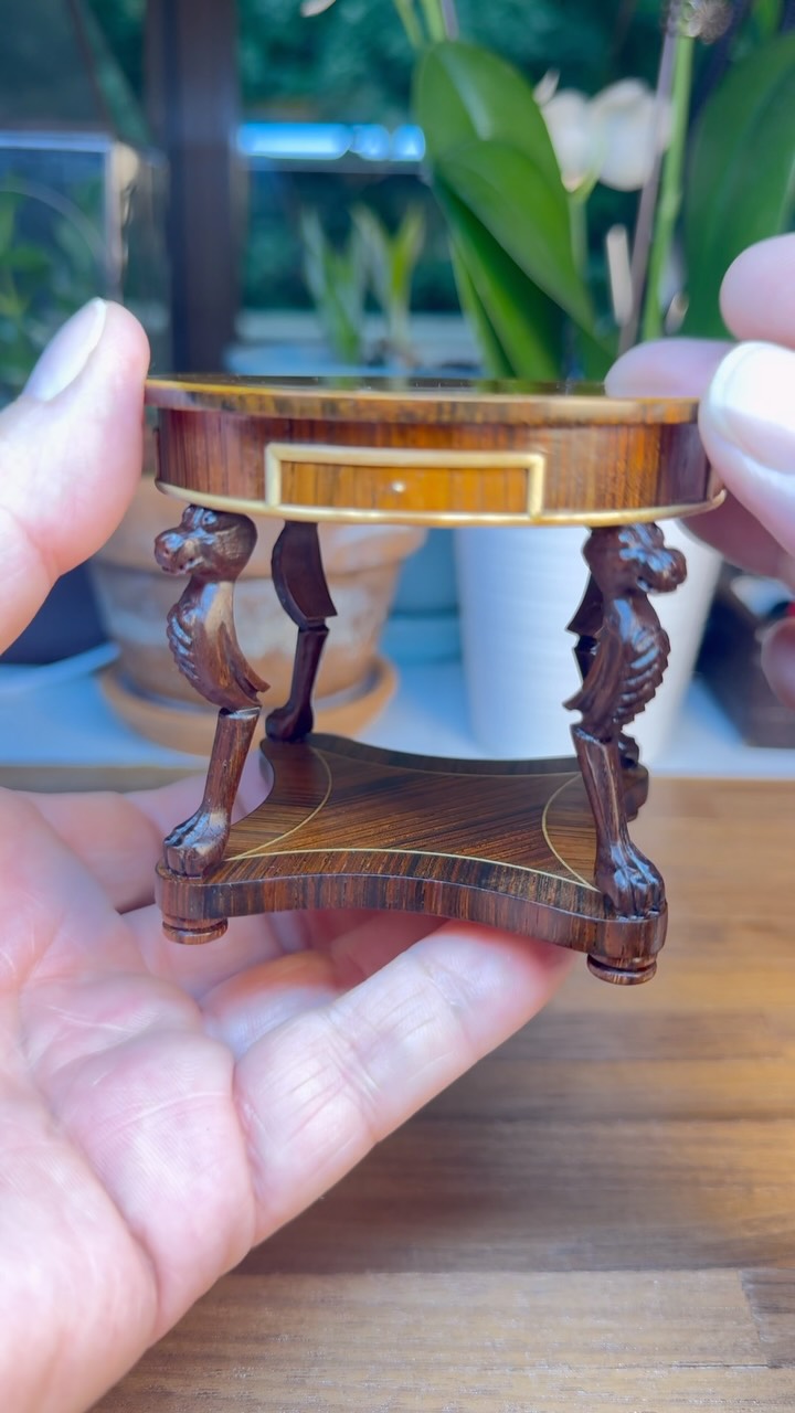 I wanted to share one of several very special masterful miniatures that are coming up in my early fall estate sale, there's a link in my bio to sign up for my newsletter so you're first to know when this event is happening. This is an extraordinary masterful drum table made by Neil Bateson out of England in 1994. What makes this piece so masterful is that it's made entirely of hardwoods with beautiful polished wood grains showing through and decorative inlay edging on the table top with hand sculpted dragon designed legs leading to claw feet ...but one of the best parts is there are four opening drawers with actual dovetail joints in front and back of each drawer which is how it's full-size counterpart would have been made. Swoon. #Dollhouse #CabinetMaking #Miniature #Artistry