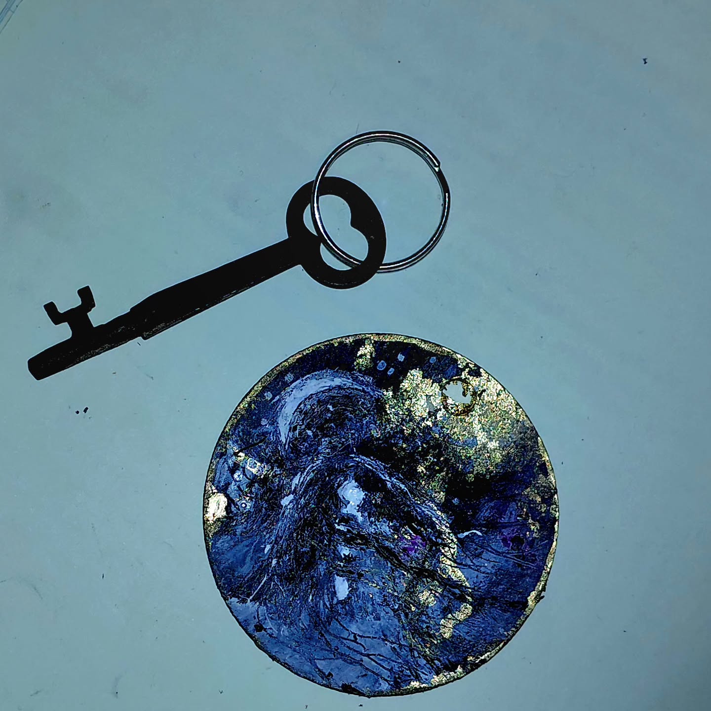"Daughter of the Moon" 2.5 inch radius (sp) little birch (?) disk. It's a keychain with a teeny tiny painting: acrylic, oil, gold leaf, ink, and oil pastel. And it somehow took a million years! So I'm terrified to varnish it when it dries because I'm so scared all the stuff will gloop up. I might experiment with a leass intricate li'l piece. #keychain #minipainting #moonart #ooak #magickey