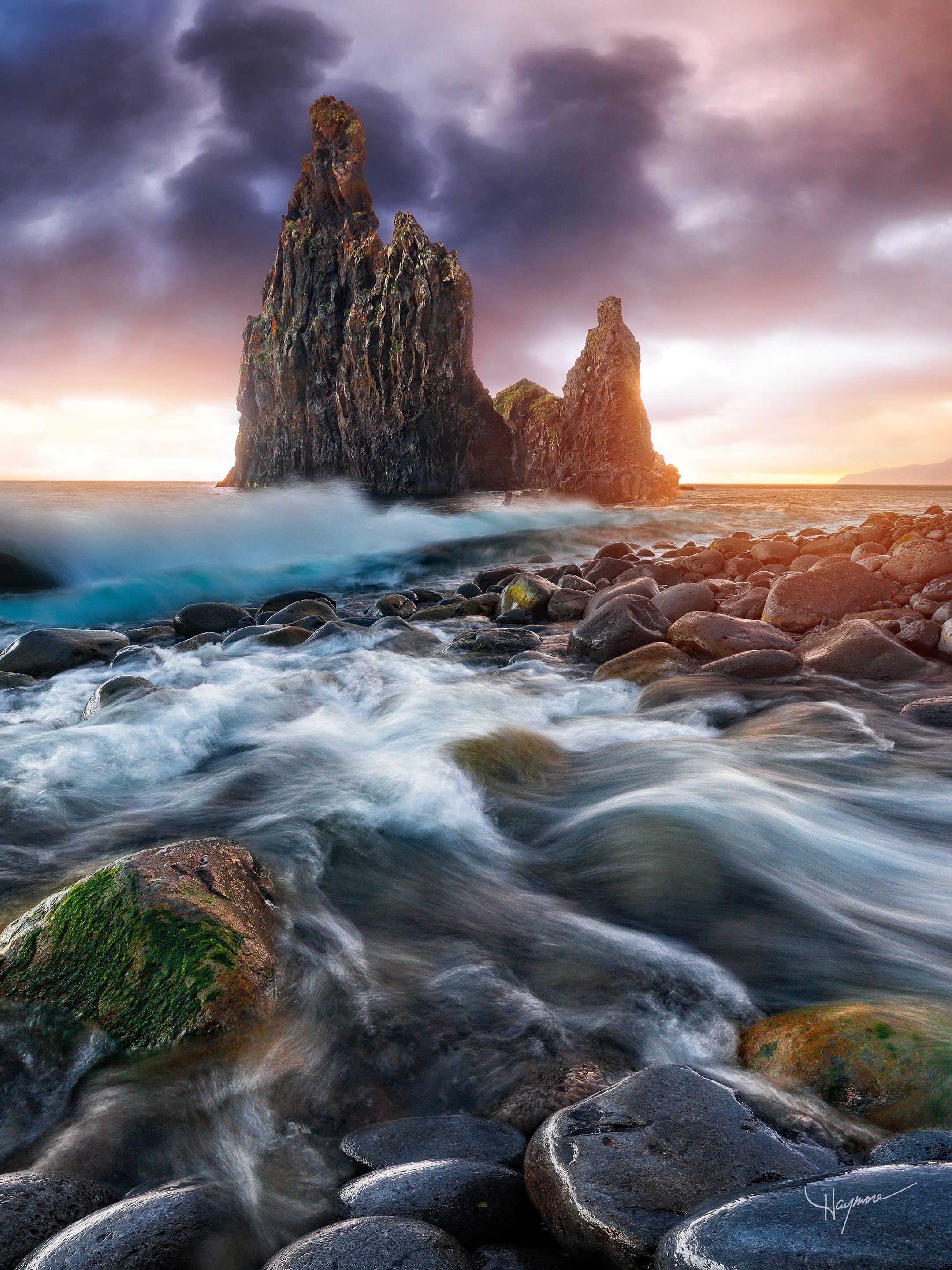 This is one of the dynamic and challenging locations in Madeira to photograph. The steep shoreline is covered wet basalt boulders, which are very slippery. Due to the steep slope of the shoreline here, the boulders are constantly moving around as the ocean waves push them upwards, only to roll back down as the water recedes.
While walk around, you can hear the rocks moving around. The desire is strong to get close to the water to capture the waves coming in, but the steep slope means the waves crash right at the edge and are hard to tell which sets are rolling in higher than the last.