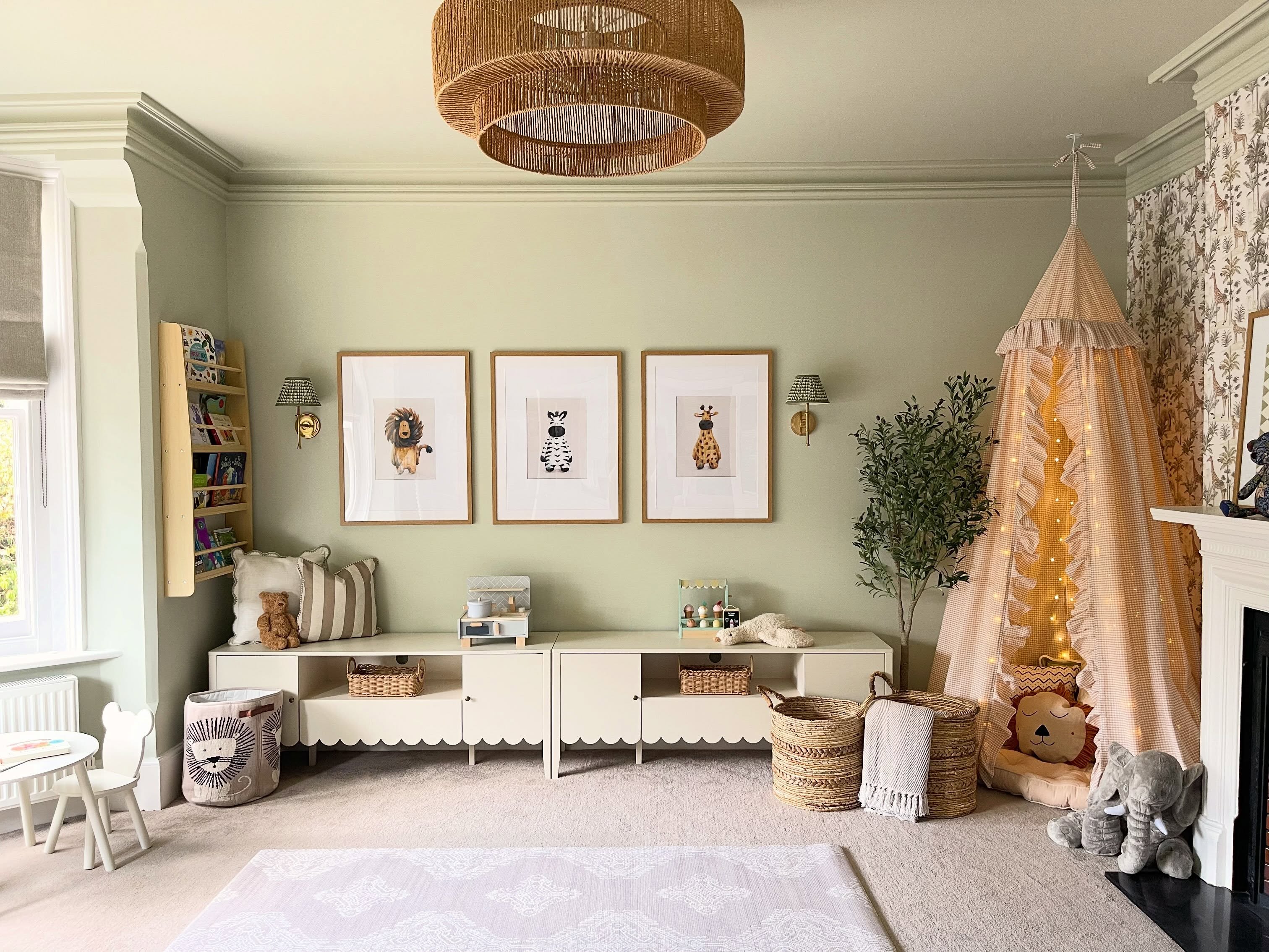 Introducing my latest playroom install from this week 🤍
This room has been transformed from an empty space into a soft, cosy playroom with lots of lovely little details.
We used Farrow & Ball Mizzle across the walls, ceiling and coving, with a beautiful safari wallpaper on the fireplace wall.
The canopy with fairy lights, cushions and floor cushions creates a cosy little den, with animal artwork and wall lights with patterned Pooky shades finishing off the space.
There’s also plenty of low-level storage for toys, books and baskets, while still leaving lots of surface space for toys and displays.
Swipe to see the before from when my clients had just moved in →
#PlayroomDesign #KidsRoomInspo #FarrowAndBall #InteriorDesign #HampshireInteriors
playroom design | kids playroom | playroom reveal | playroom transformation | children’s room | kids room inspiration | Farrow & Ball Mizzle | soft green interiors | safari wallpaper | playroom storage | toy storage | canopy den | kids reading nook | Pooky lighting | children’s artwork | family home interiors | cosy interiors | modern country interiors | Hampshire interior designer | Surrey interior designer