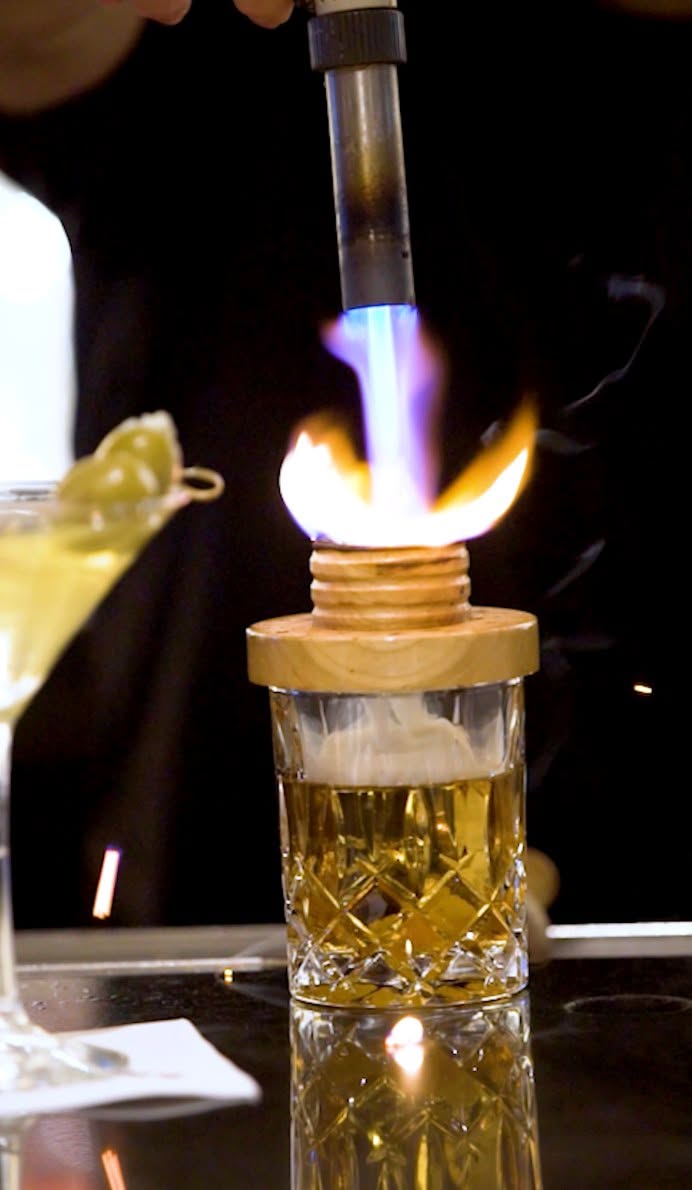 Why smoke a whiskey that's already good on its own?
Because the smoke pulls out a deeper char and a subtle woodsy sweetness that sits underneath the whiskey's own caramel and oak, rounding out the whole pour. Poured first, then smoked, right at the bar.
It's details like this that make our bar what it is. What’s your go-to drink order?
📍 Uptown Dallas | Reserve via link in bio.
#NickAndSams #DallasCocktails #DallasBar #UptownDallas