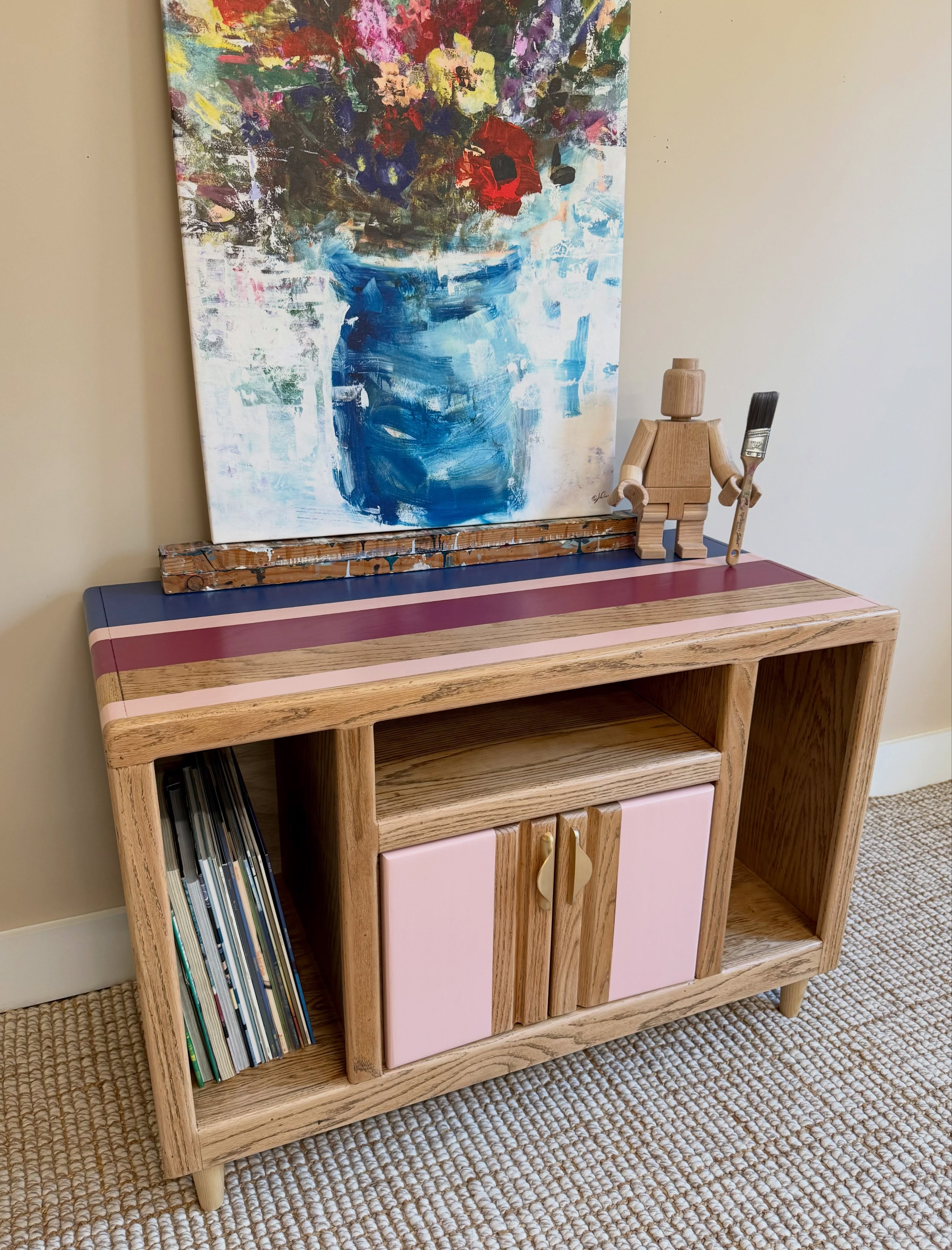 Good storage should never feel bulky or predictable. For this oak media cabinet, we paired hand-painted modern stripes with warm, exposed natural woodgrain and curved gold-tone pulls. Inside, there is generous shelving designed to hide media boxes, board games, or records without losing an ounce of character.
#twopoppiesdesign #mediaconsole #oakfurniture #paintedfurniture #vintagemarketdays